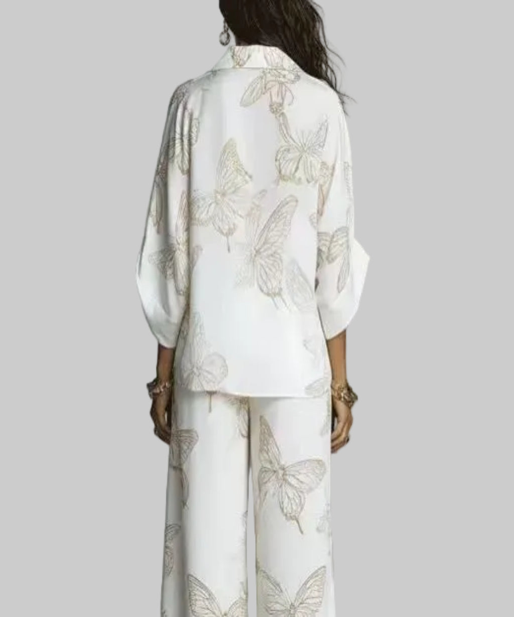 Person wearing a white outfit with butterfly patterns against a gray background