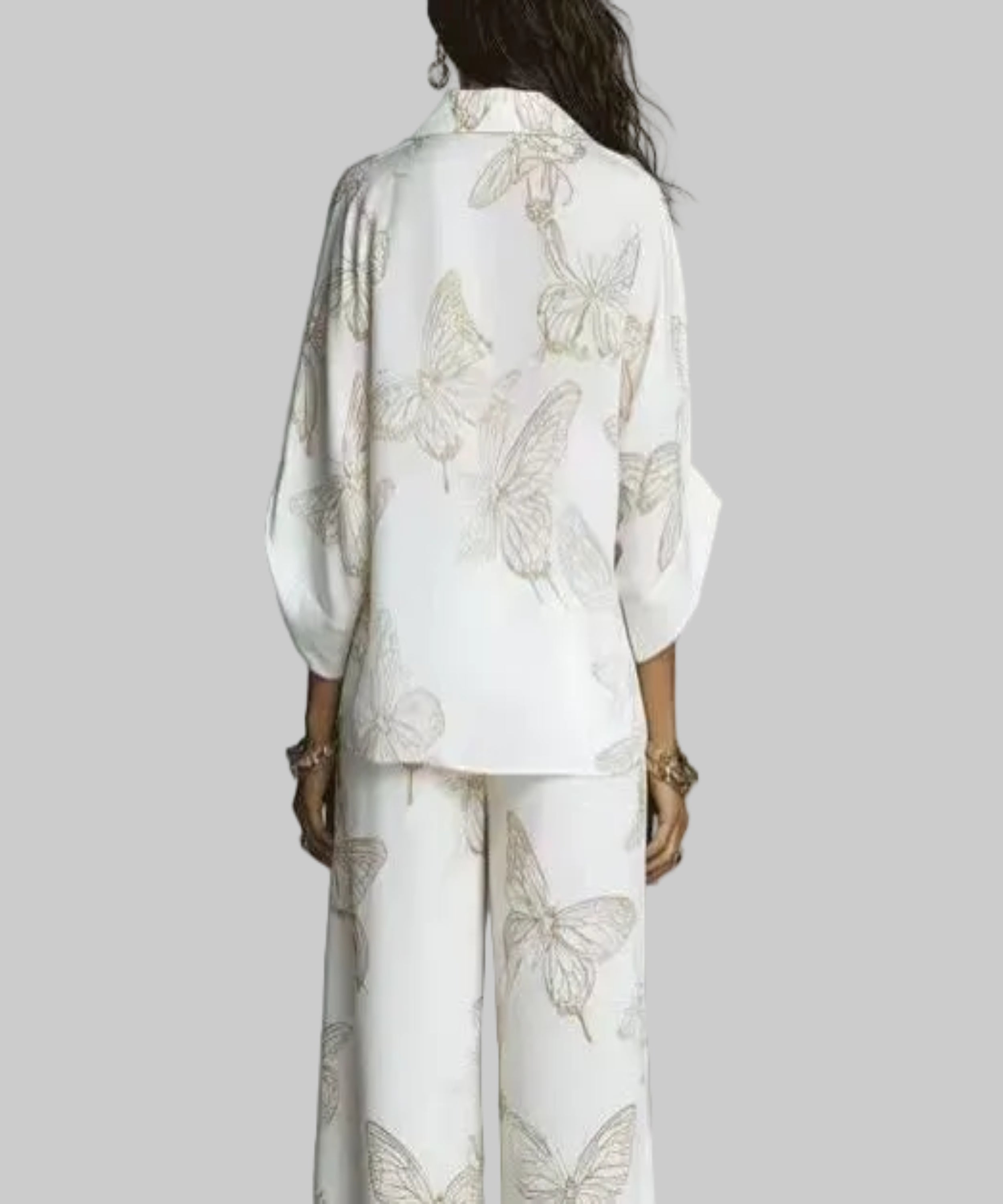 Person wearing a white outfit with butterfly patterns against a gray background