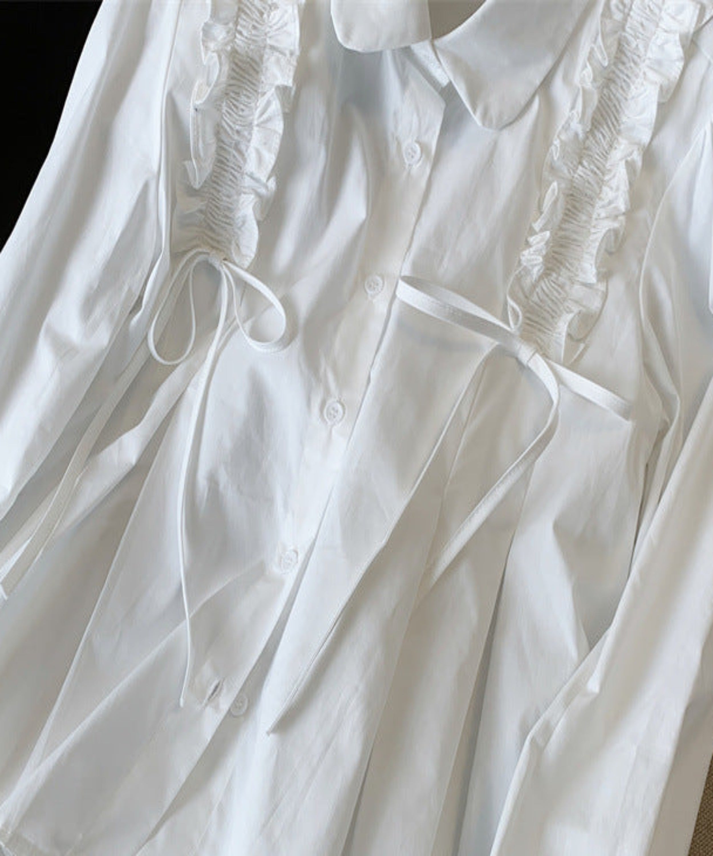 White shirt with ruffled details on a surface