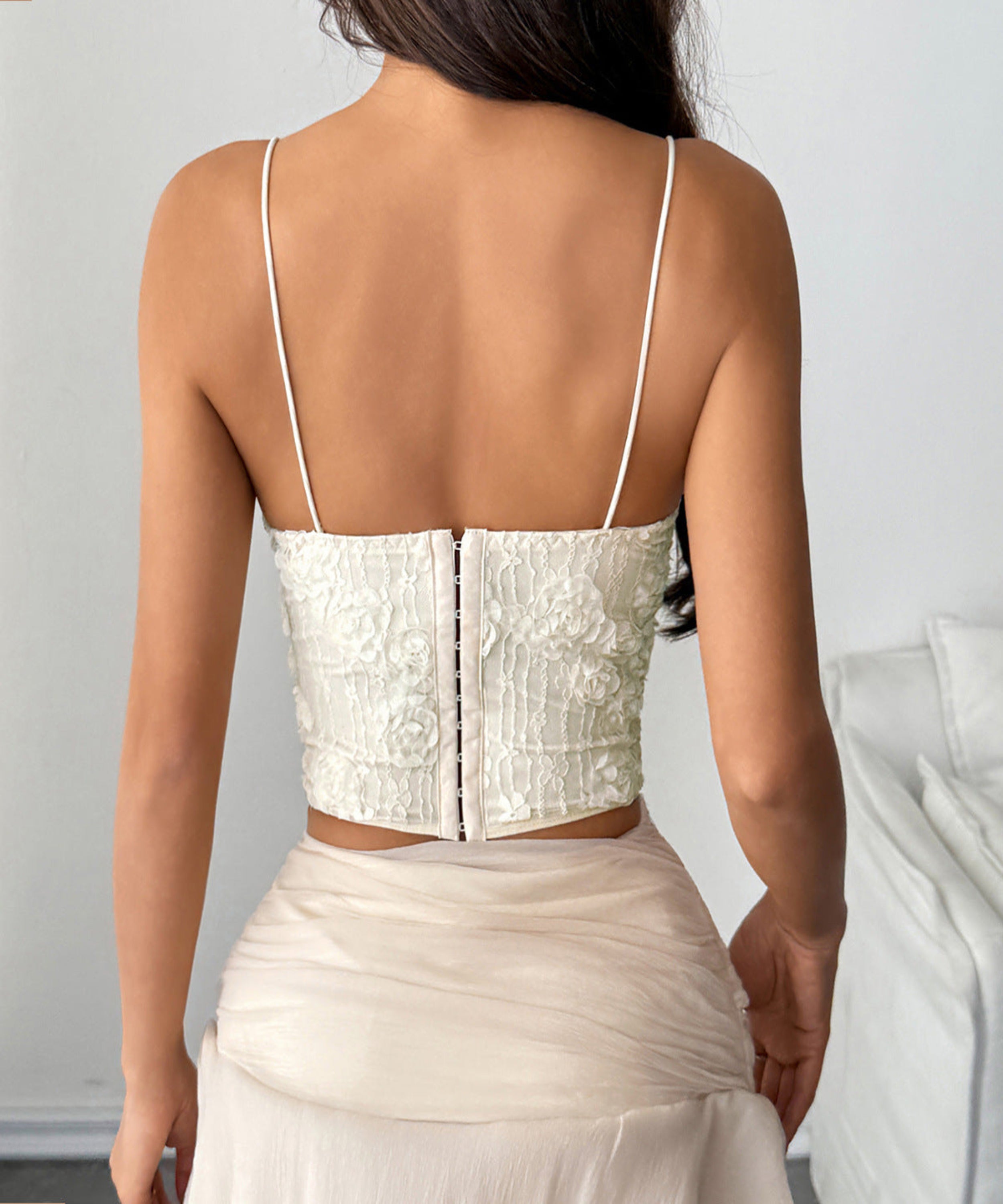 Woman wearing a white lace top and skirt set against a plain background