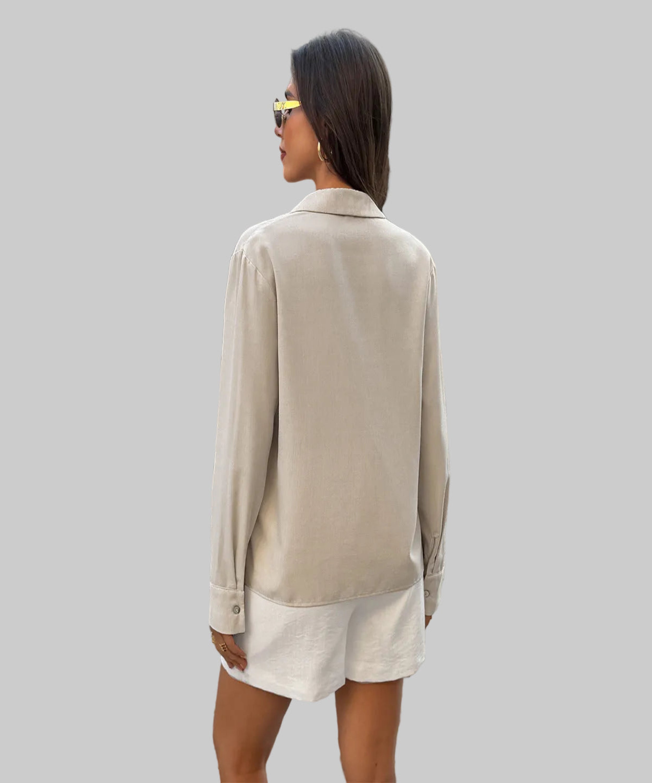 Woman wearing a beige blazer and white shorts walking on a cobblestone street.