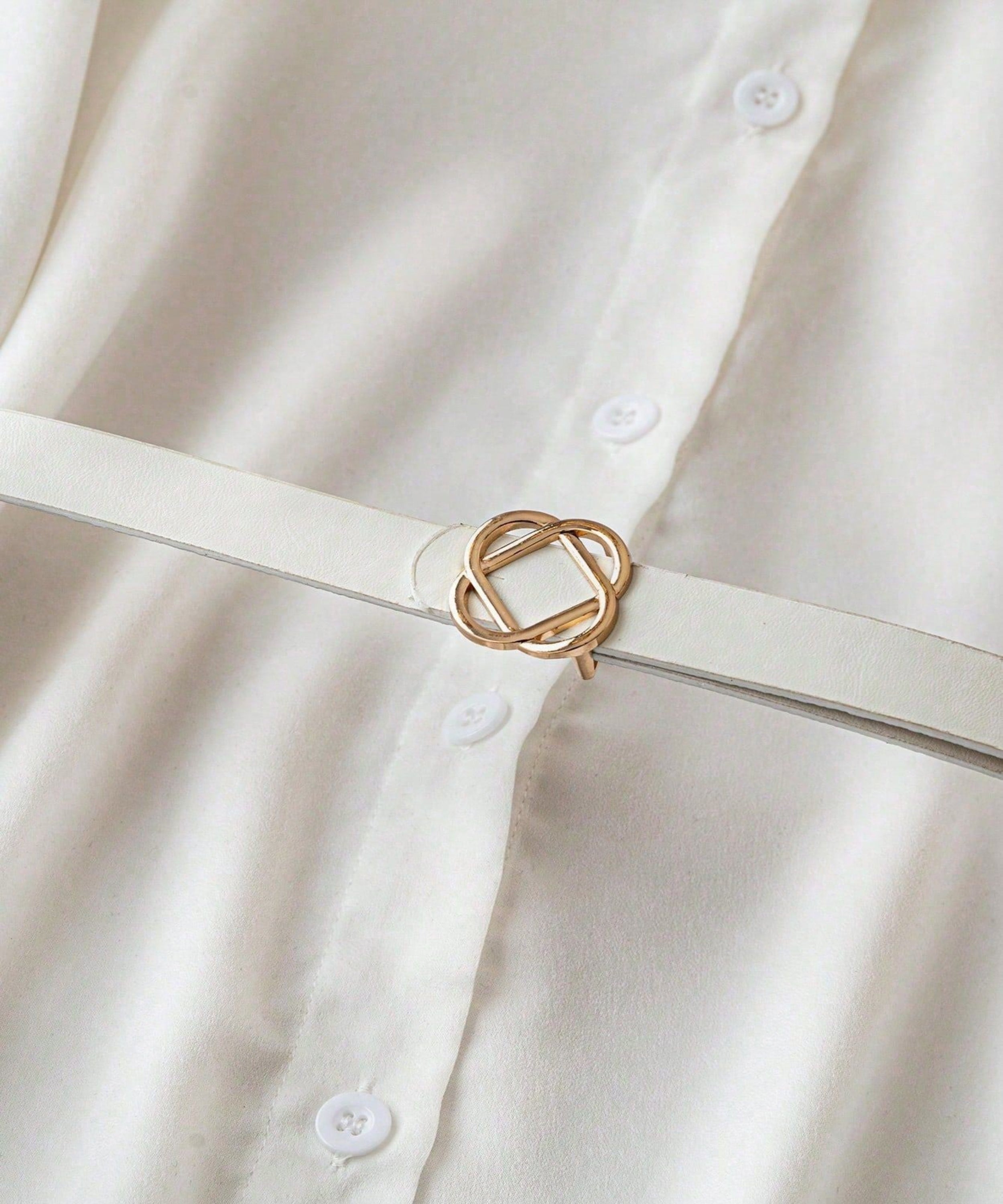 White shirt with a gold belt buckle on a plain background