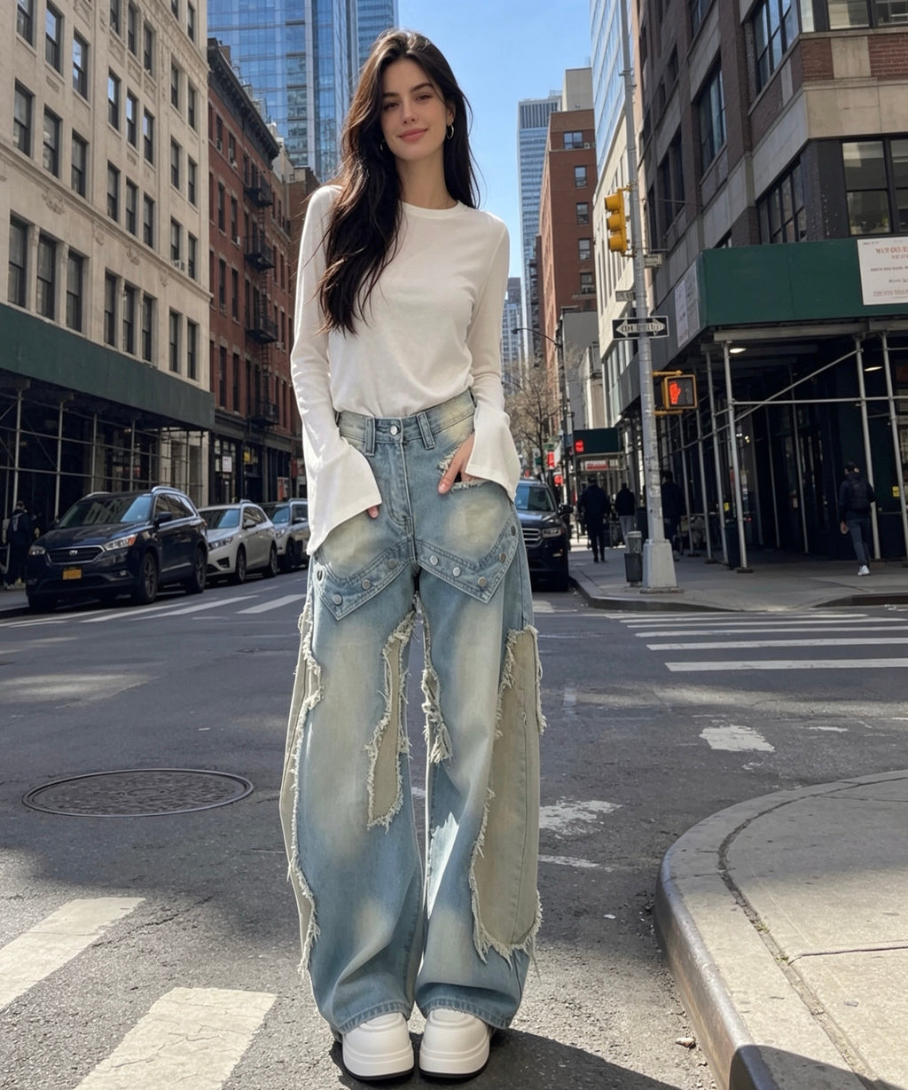 Woman in white top and ripped jeans standing on a city street.