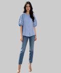 Woman in a light blue shirt and jeans standing on a white  background