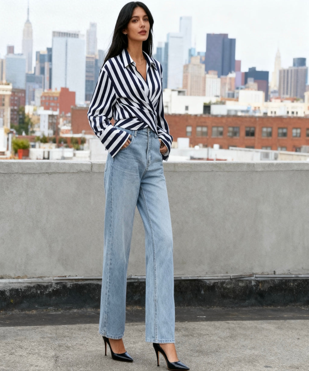 Woman in a striped shirt and jeans standing on a rooftop with a city skyline in the background