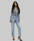 Woman in a striped shirt and jeans standing on white background.