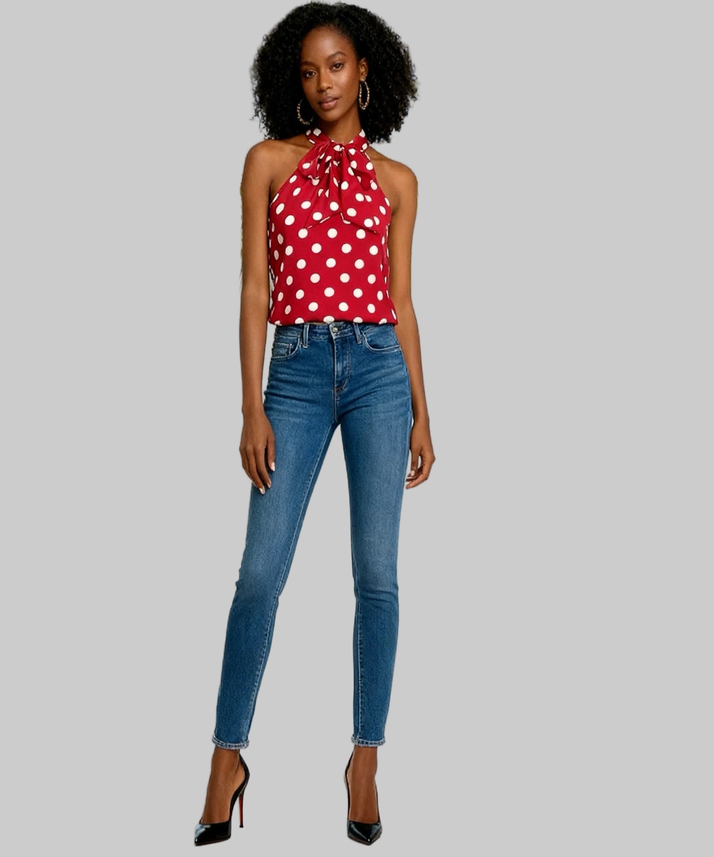 Woman wearing a red polka dot top and blue jeans in a white background