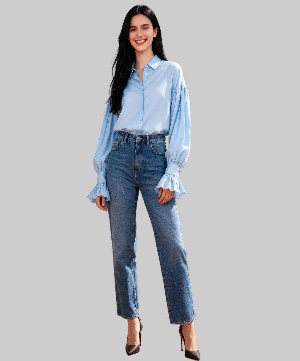 Woman wearing a light blue shirt and jeans standing on a white background.