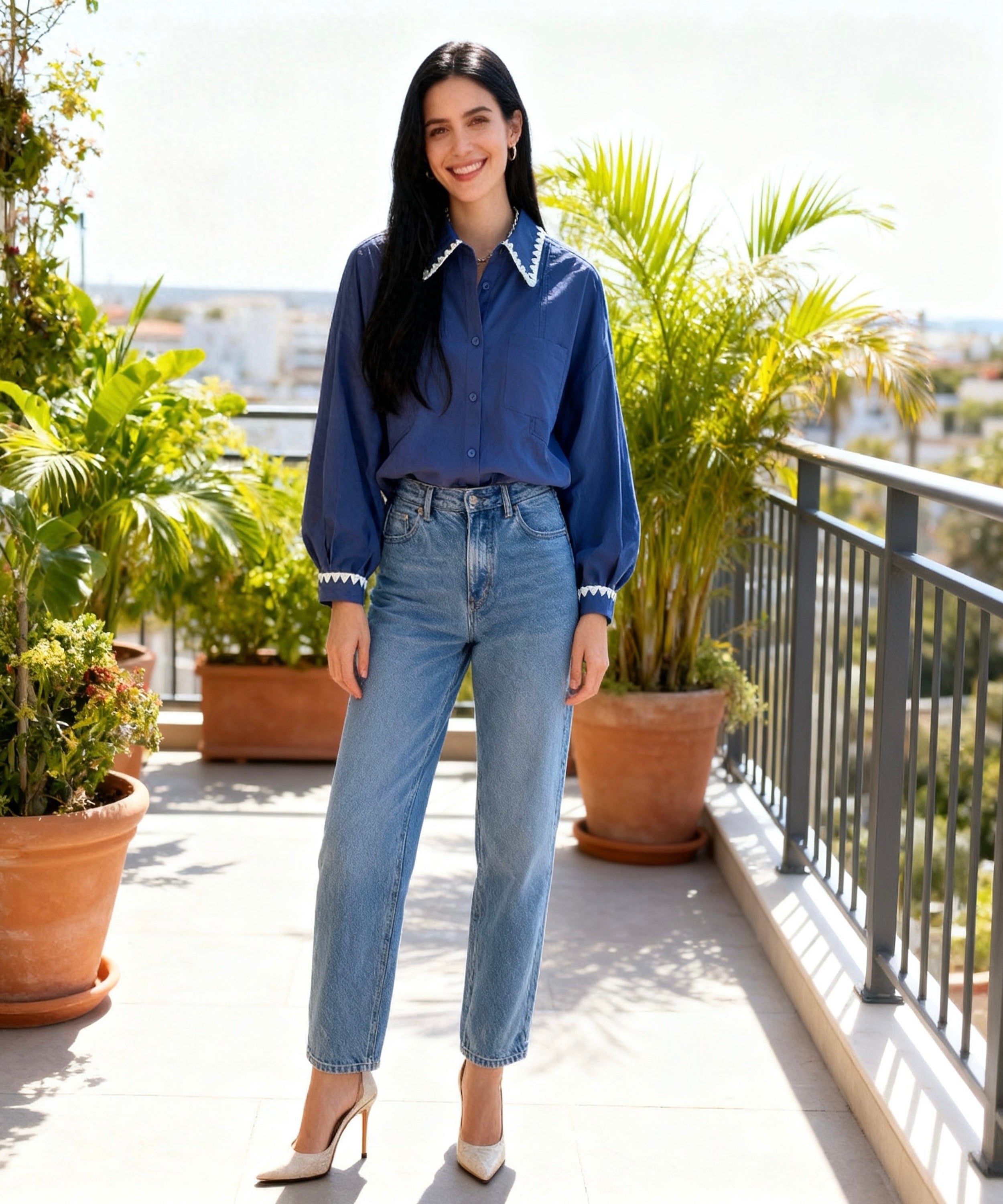 Woman in a blue shirt and jeans standing on a balcony with plants