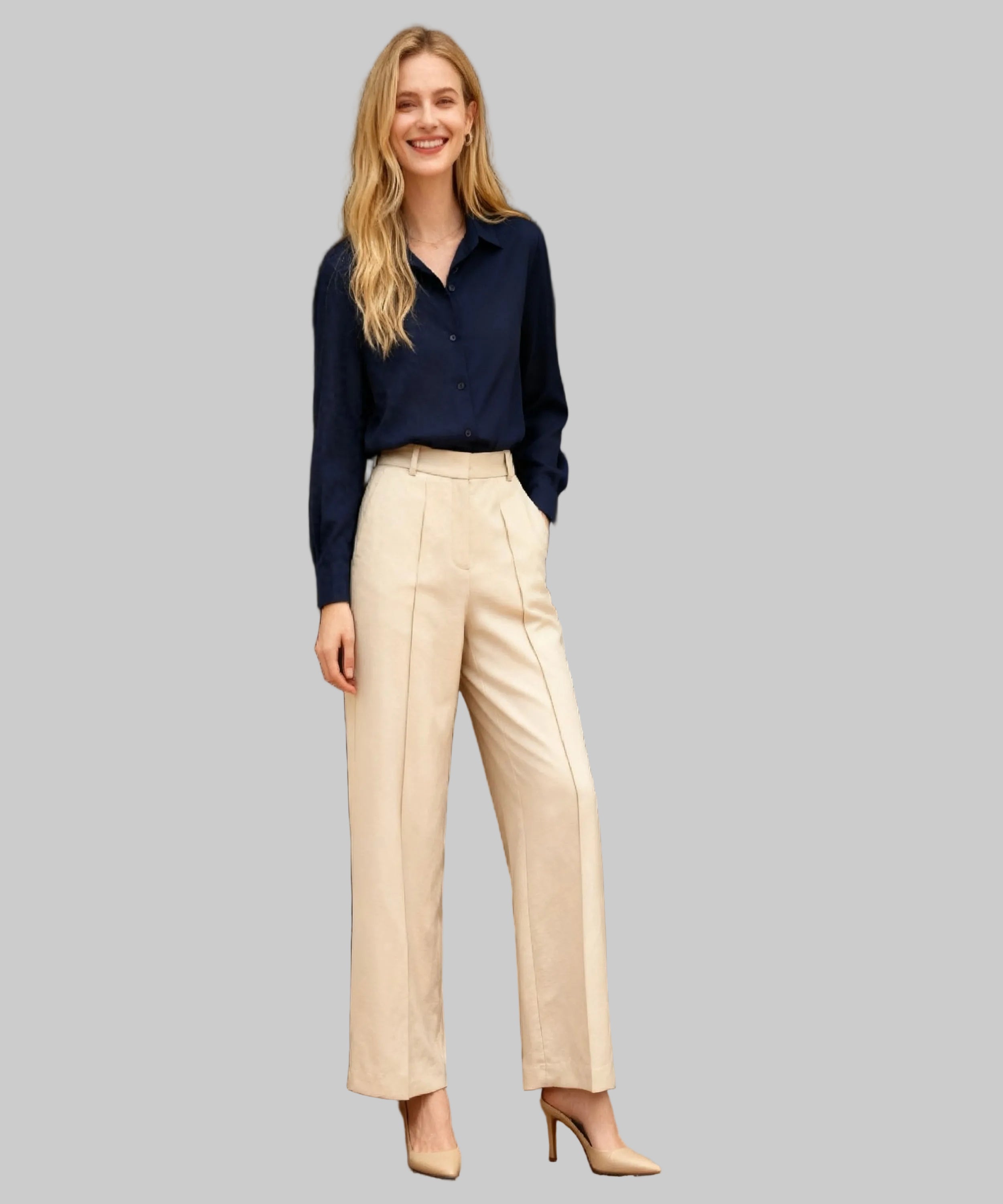 Woman wearing a navy shirt and beige pants standing in a white background.