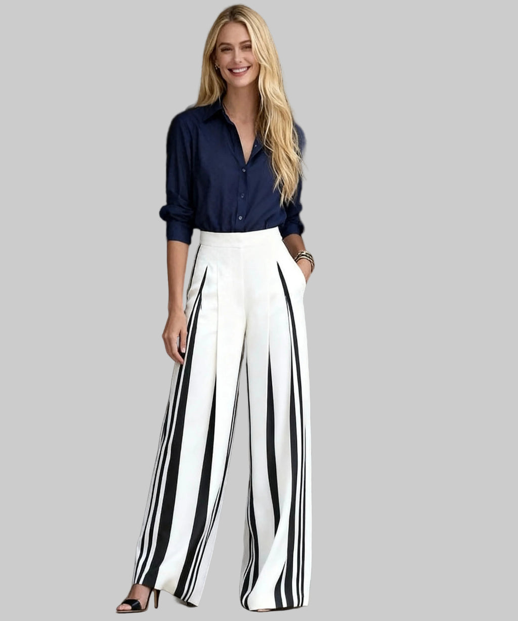 Woman wearing a navy shirt and black and white striped pants standing in a white background.