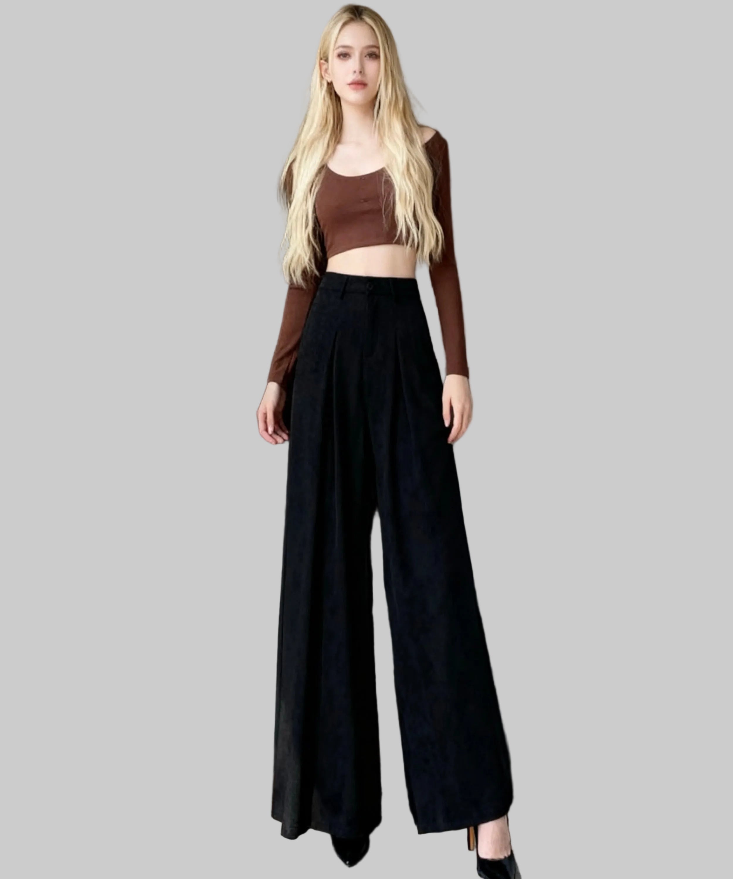 Woman wearing a brown top and black wide-leg pants standing in a white background.