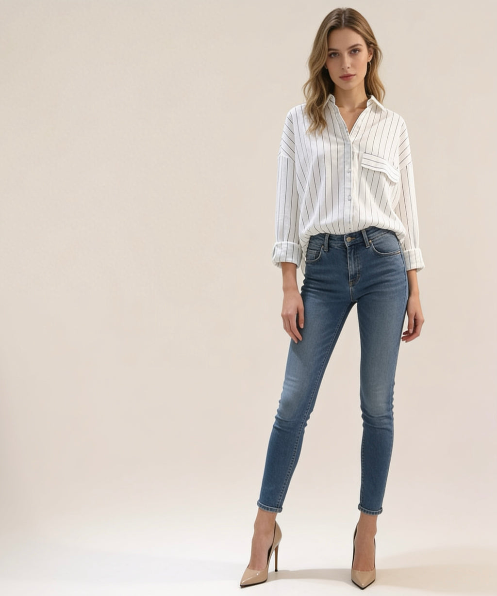 Woman wearing a striped shirt and blue jeans on a plain background