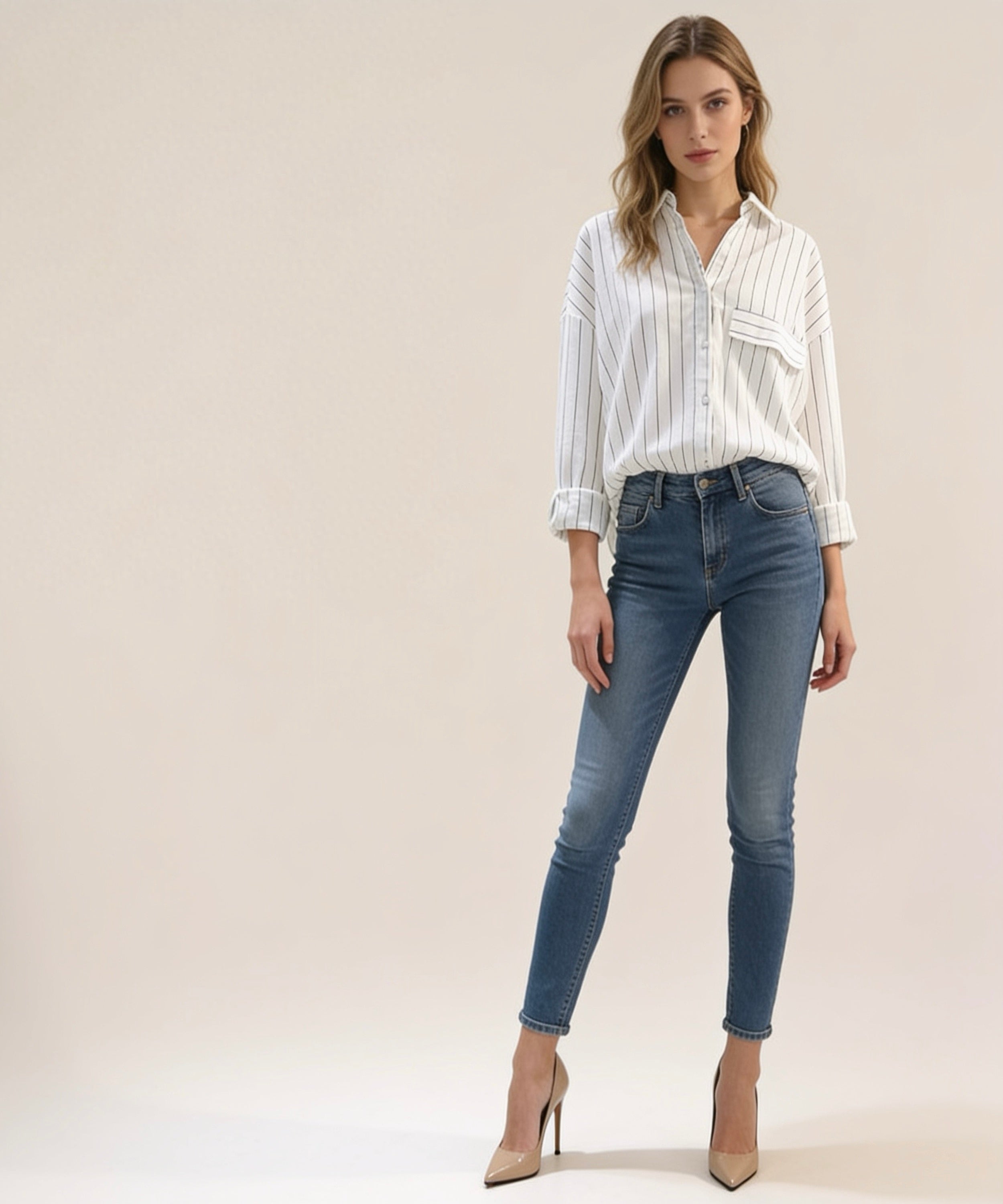 Woman wearing a striped shirt and blue jeans on a plain background