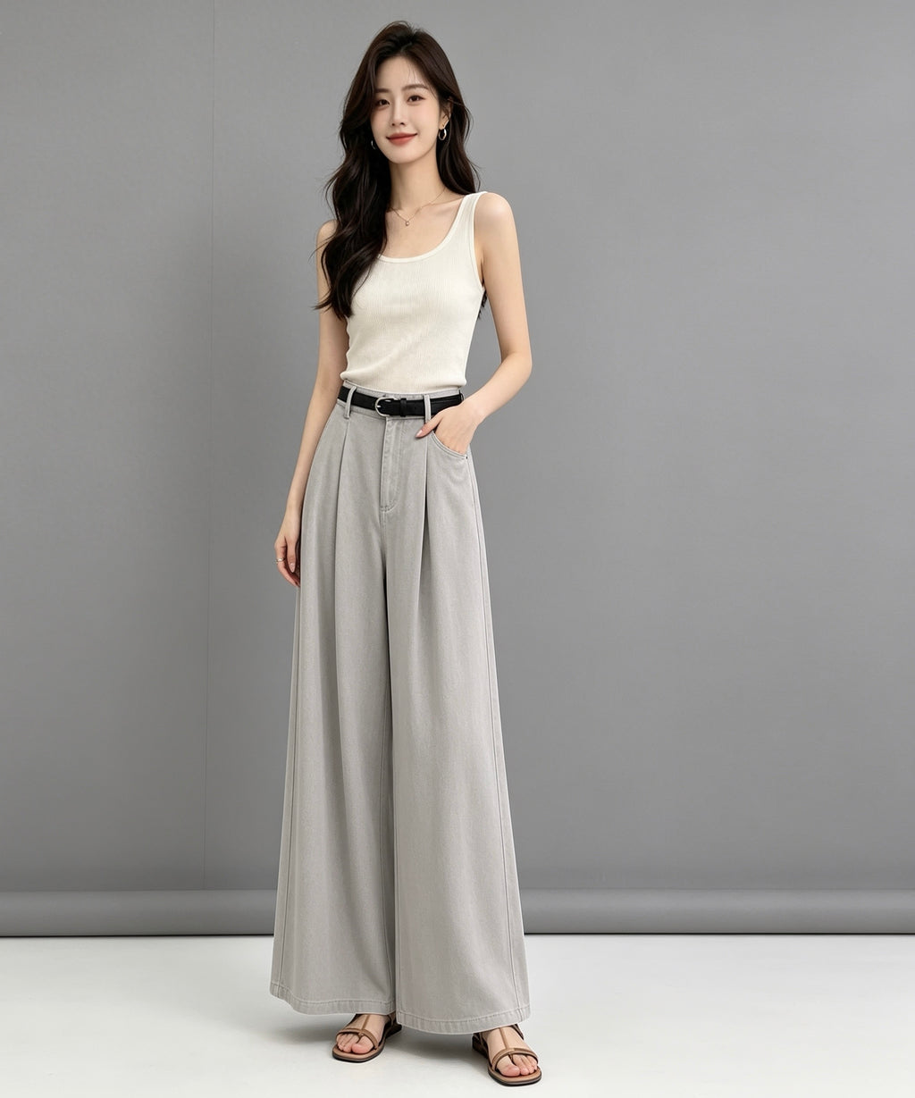 Woman wearing a white sleeveless top and gray wide-leg pants against a gray background