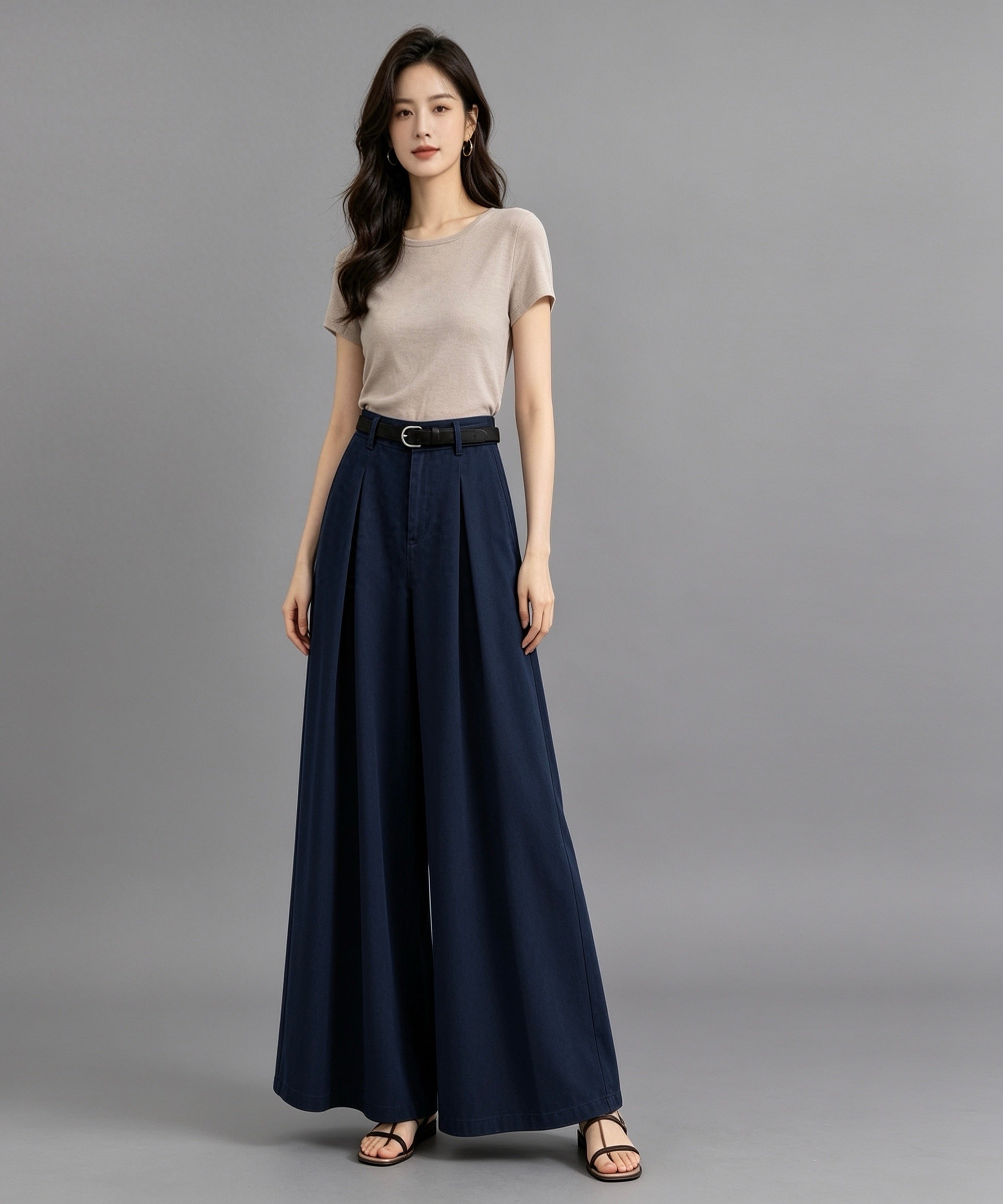 Woman wearing a beige top and navy blue skirt on a gray background