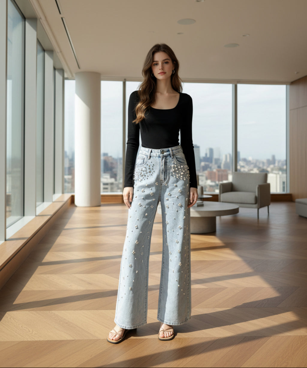 Woman wearing a black long-sleeve top and light blue jeans with embellishments in a living room.