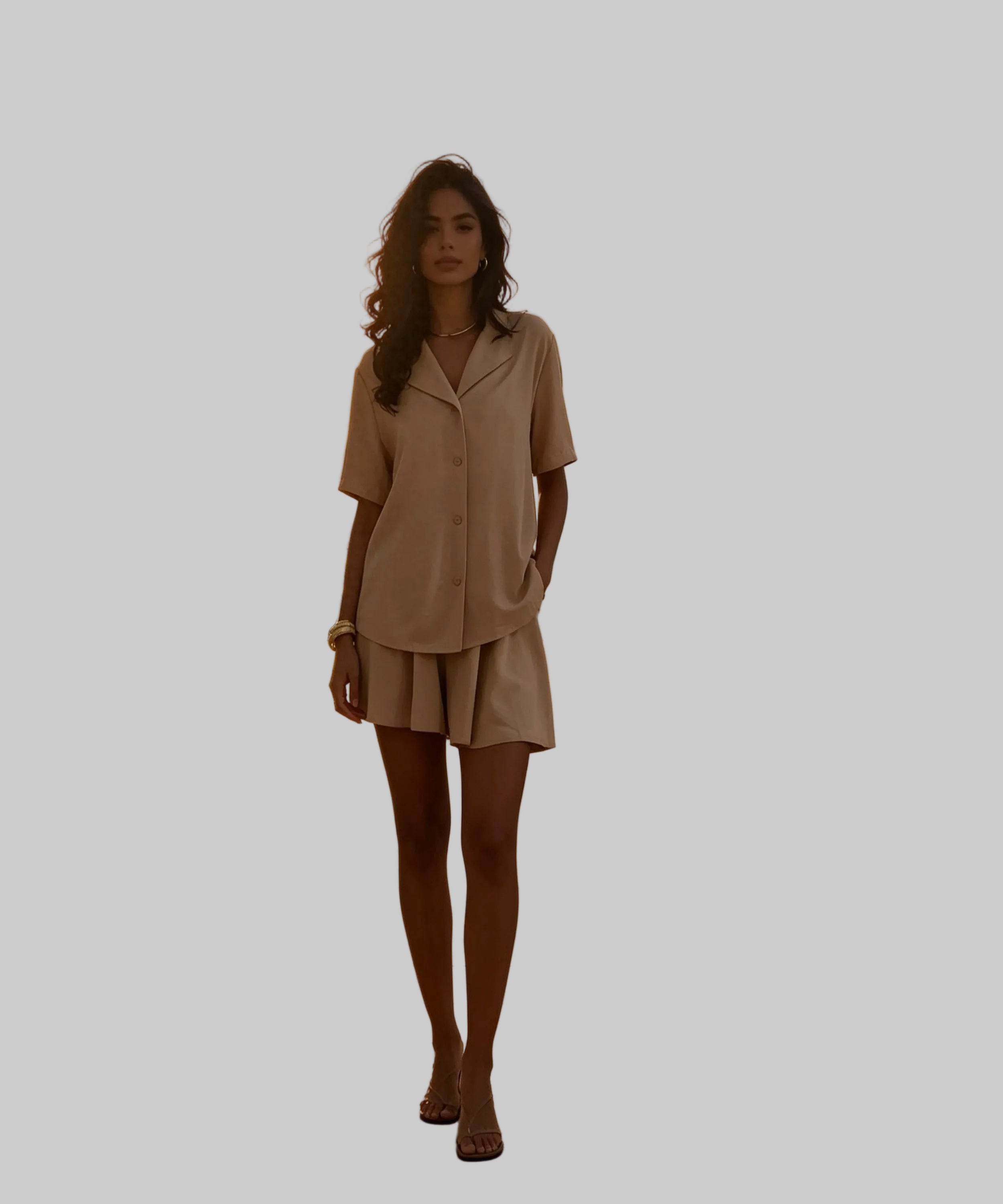 Woman in a beige outfit standing on a white background.