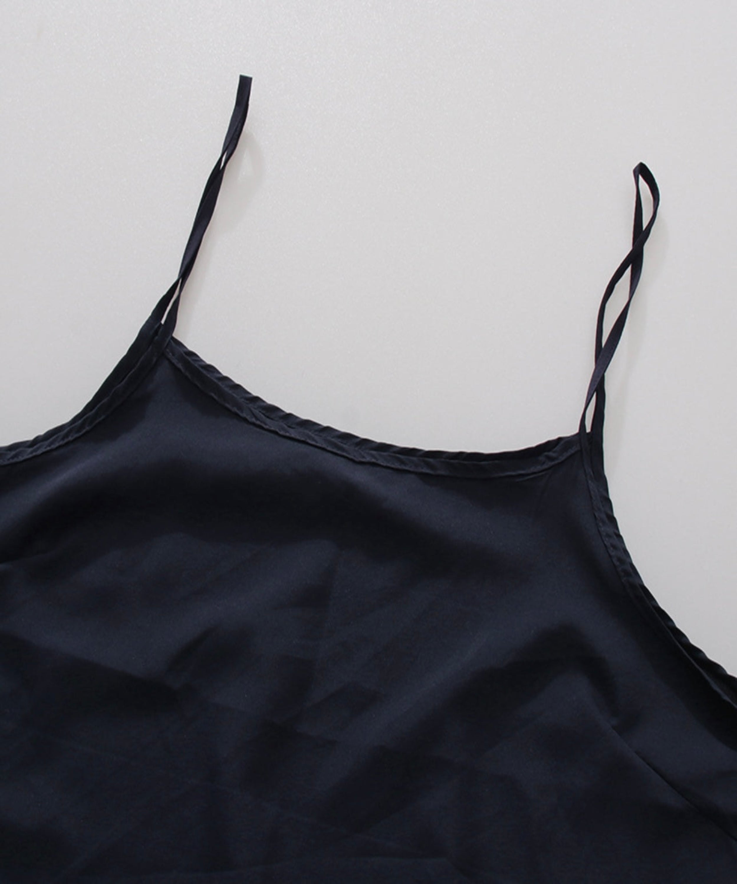 Black satin slip dress on a light gray background