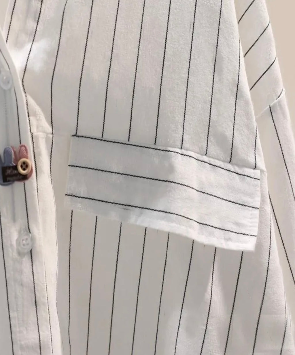Close-up of a white shirt with black pinstripes and a pocket.