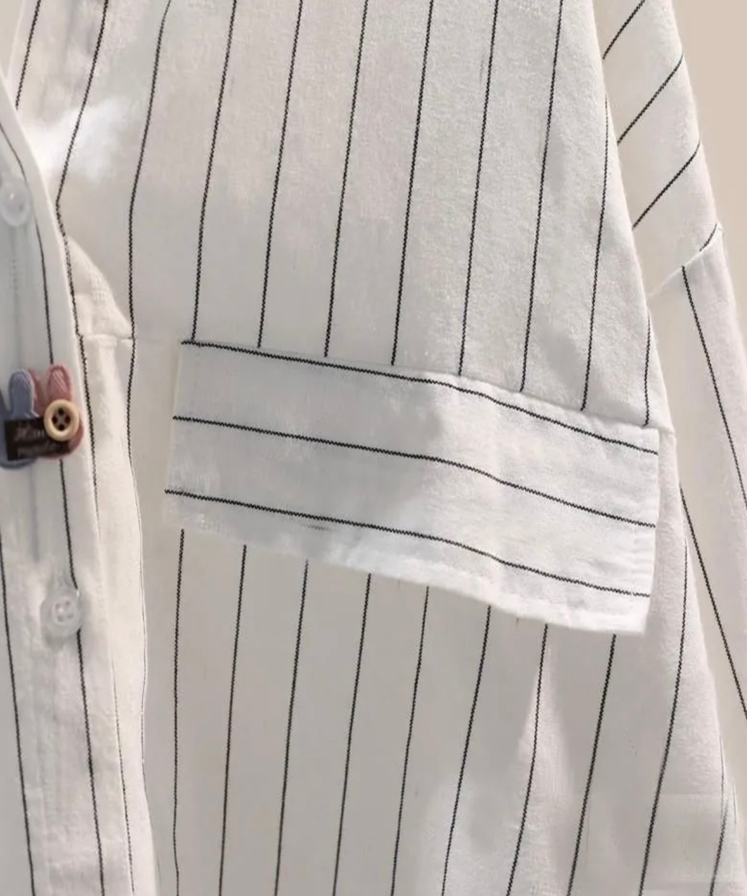 Close-up of a white shirt with black pinstripes and a pocket.