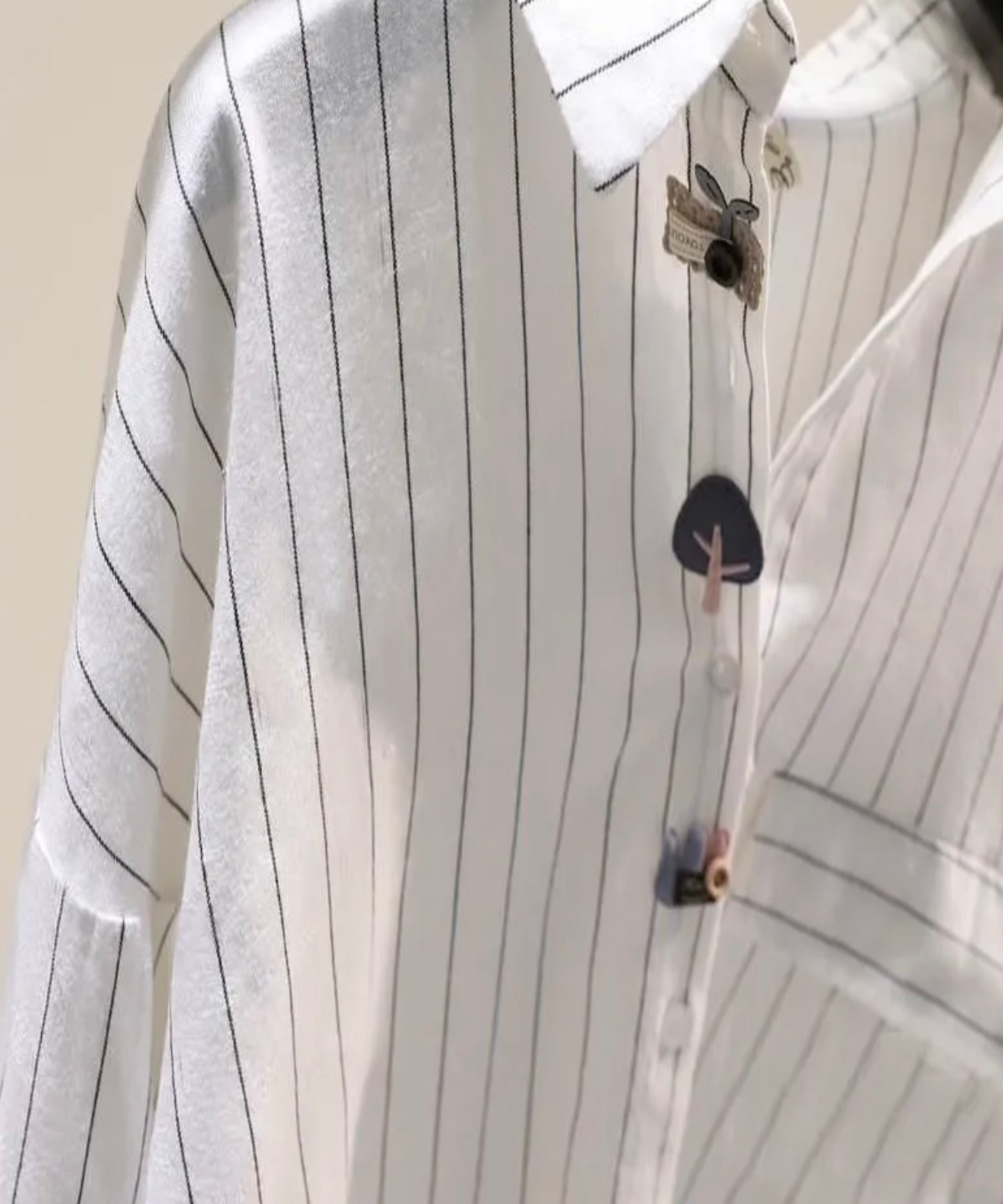 White shirt with black pinstripes on a mannequin against a beige background