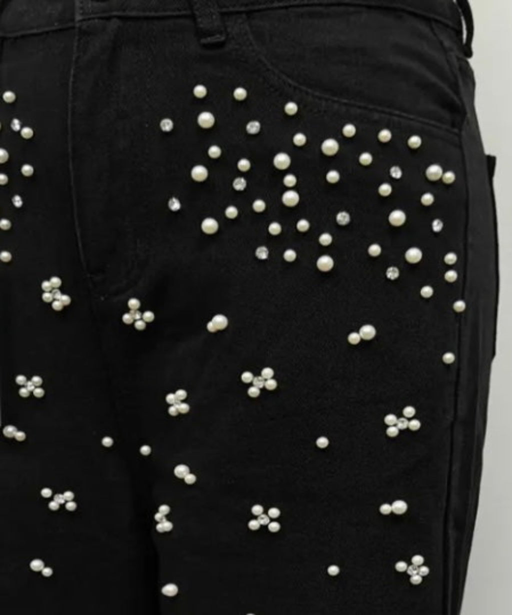 Black pants with pearl embellishments on a plain background