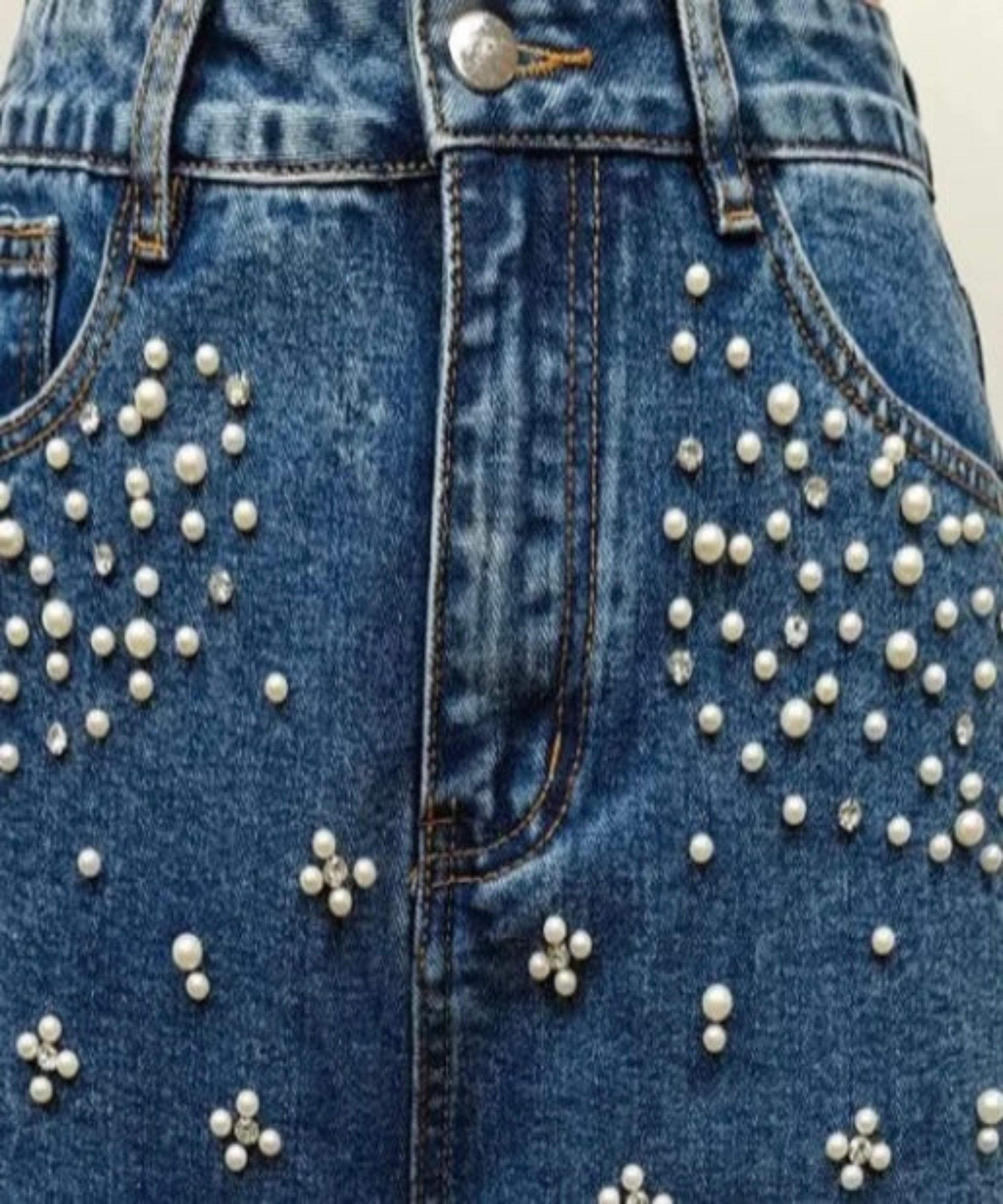 Blue denim jacket with pearl embellishments on a plain background