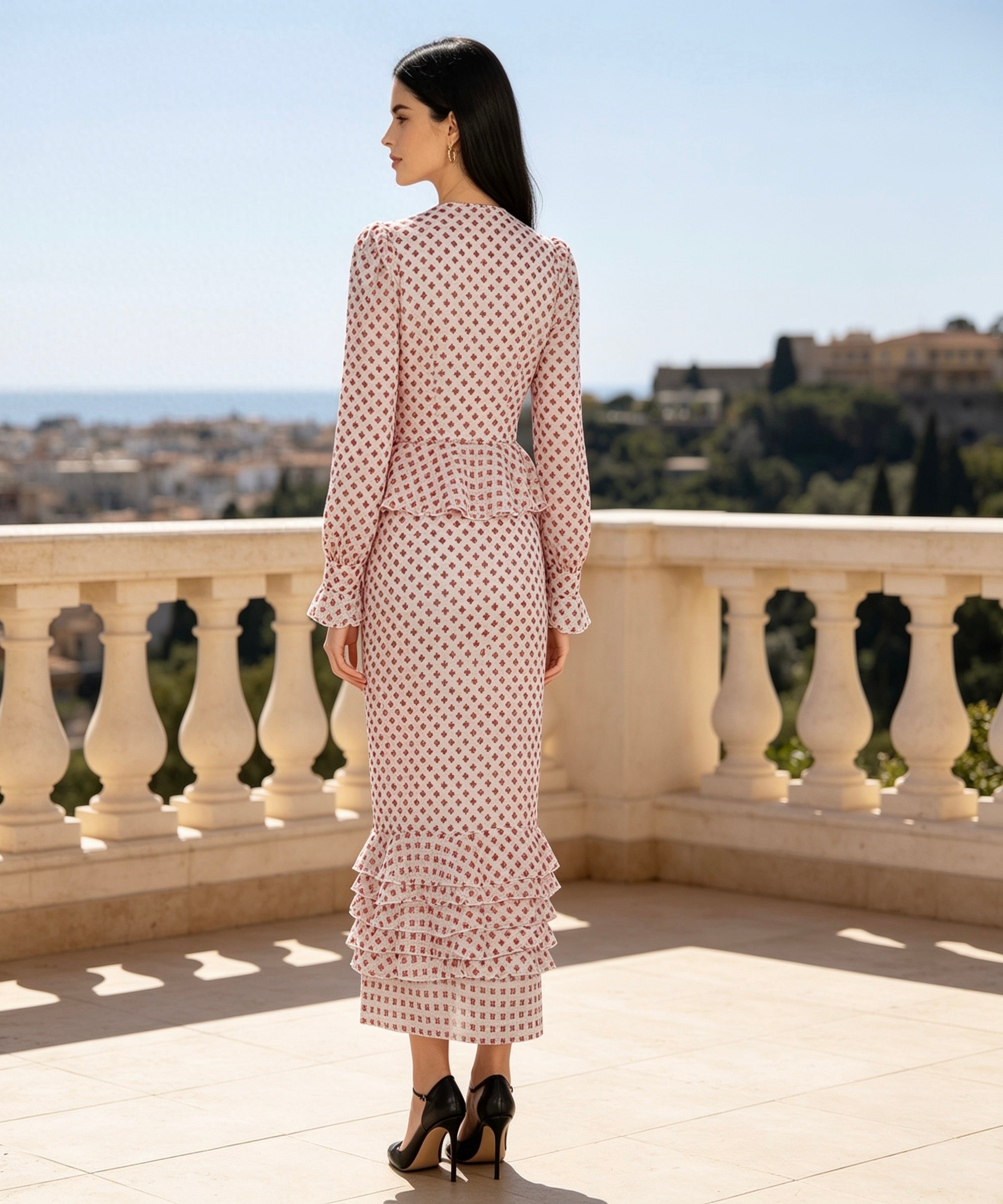Woman in a polka dot dress standing on a balcony with a scenic view.
