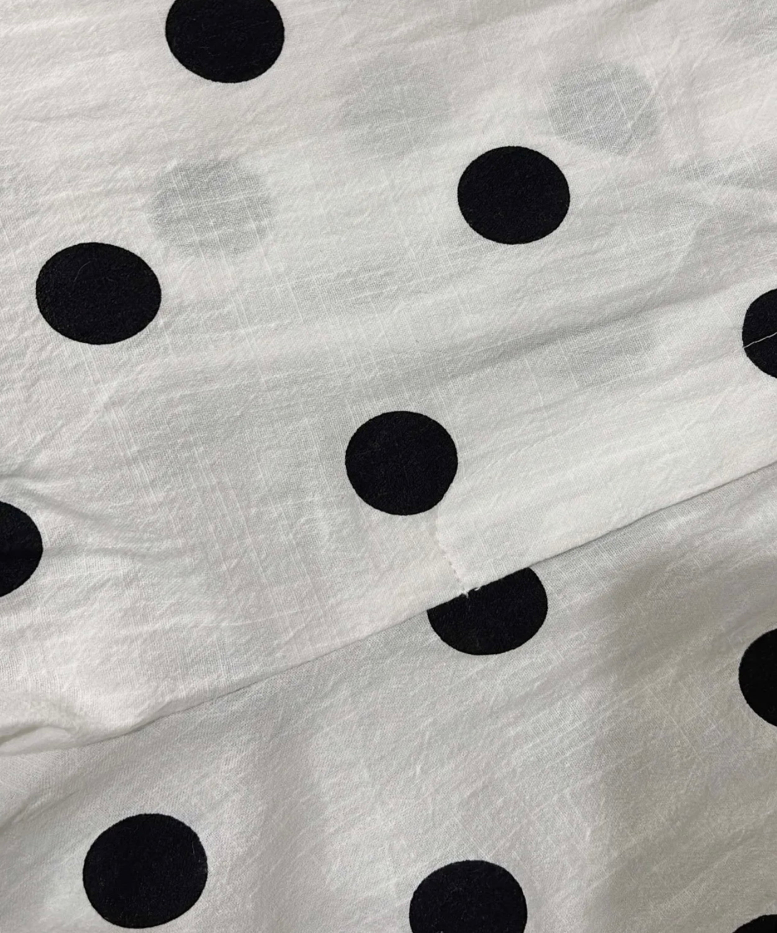 Close-up of white fabric with large black polka dots