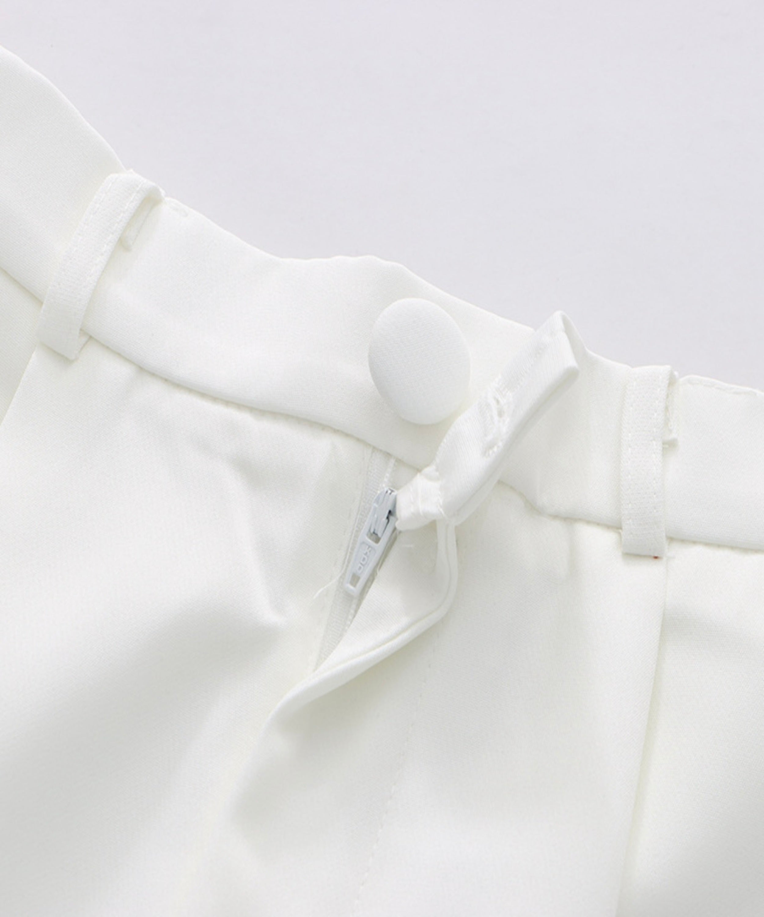 Close-up of a white shirt with a collar and label on a light gray background