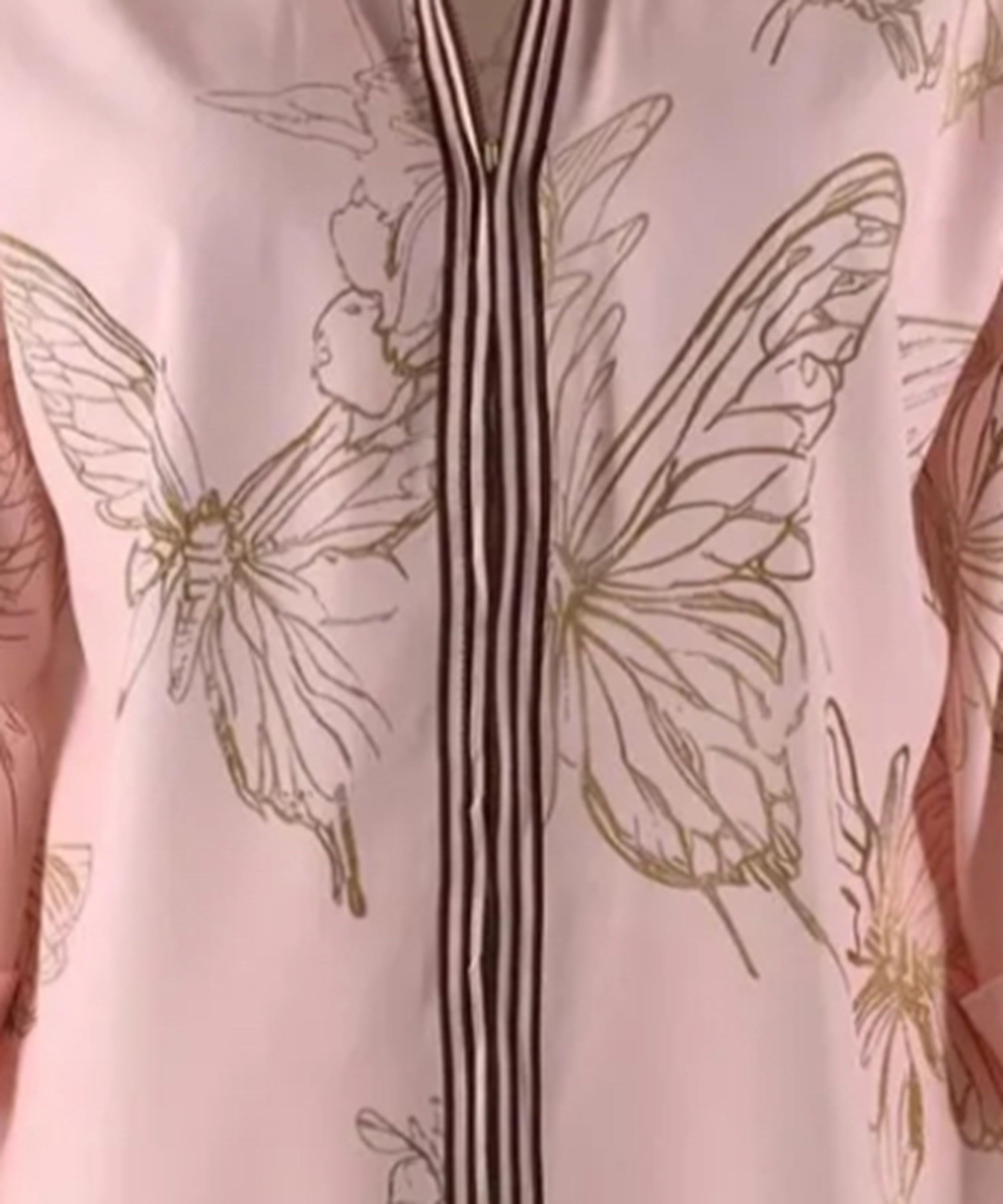 Close-up of a garment with butterfly designs on a light pink background