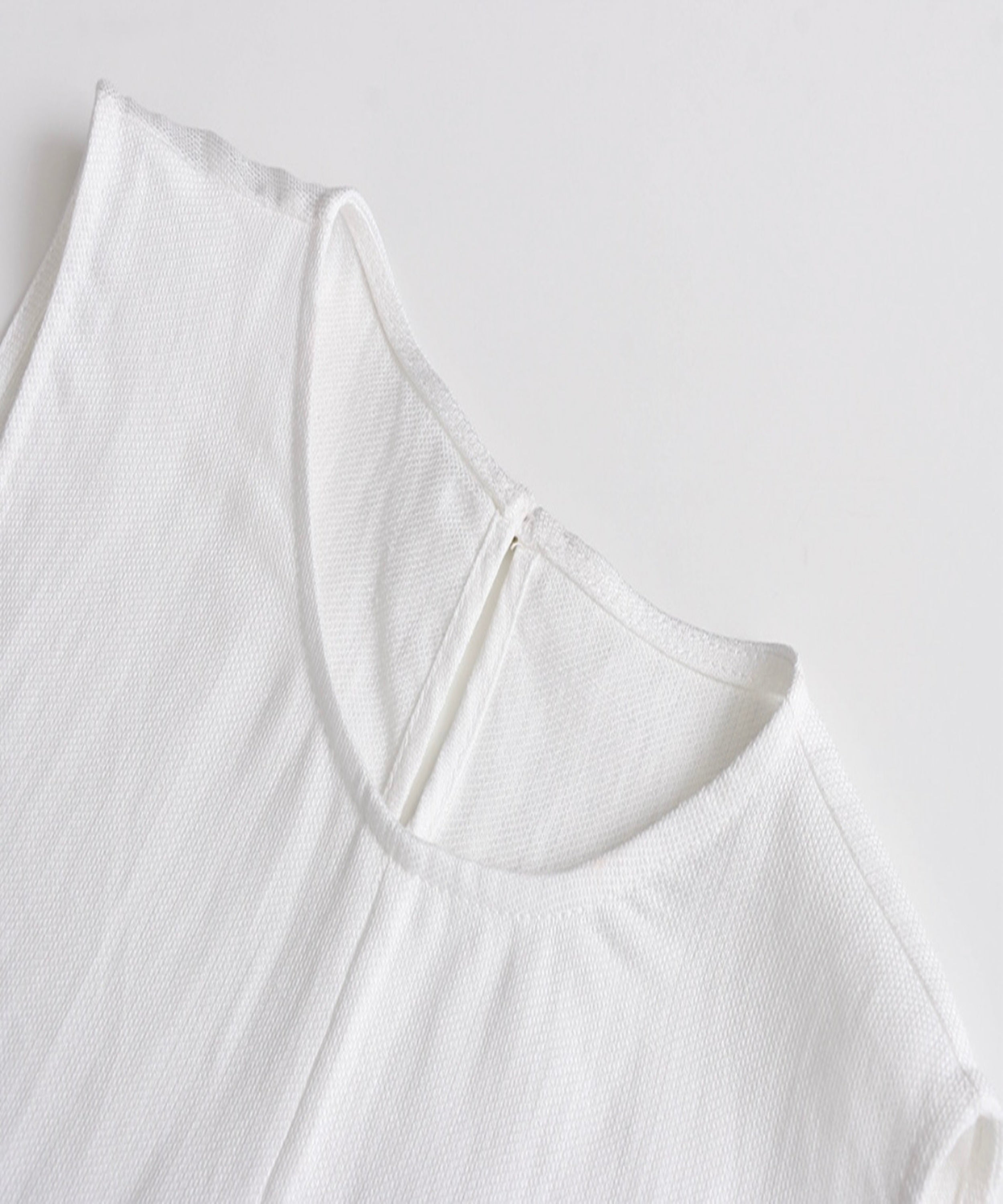 Close-up of a white sleeveless top on a light gray background