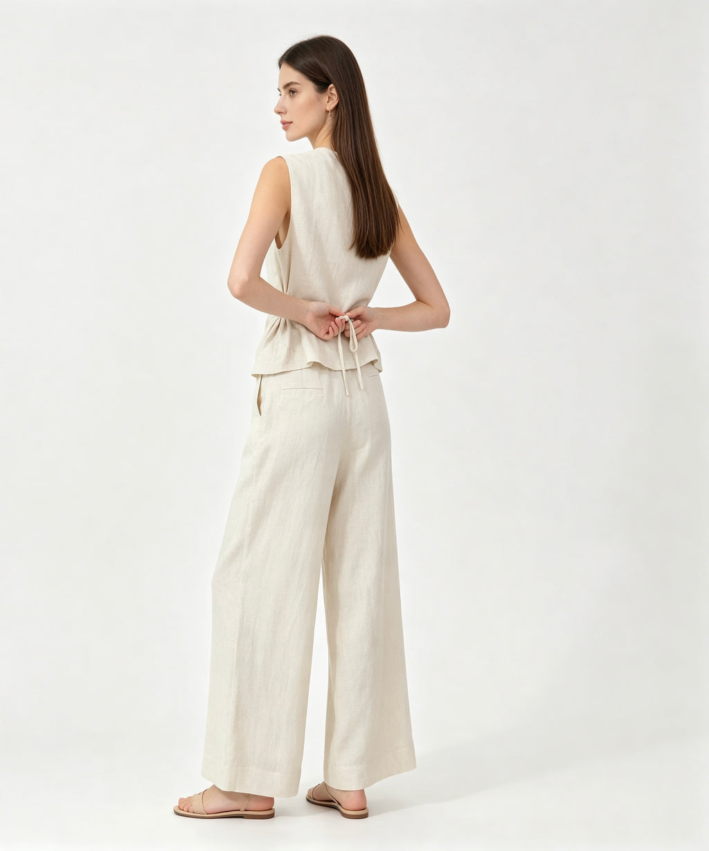 Woman wearing a white sleeveless top and wide-leg pants on a white background