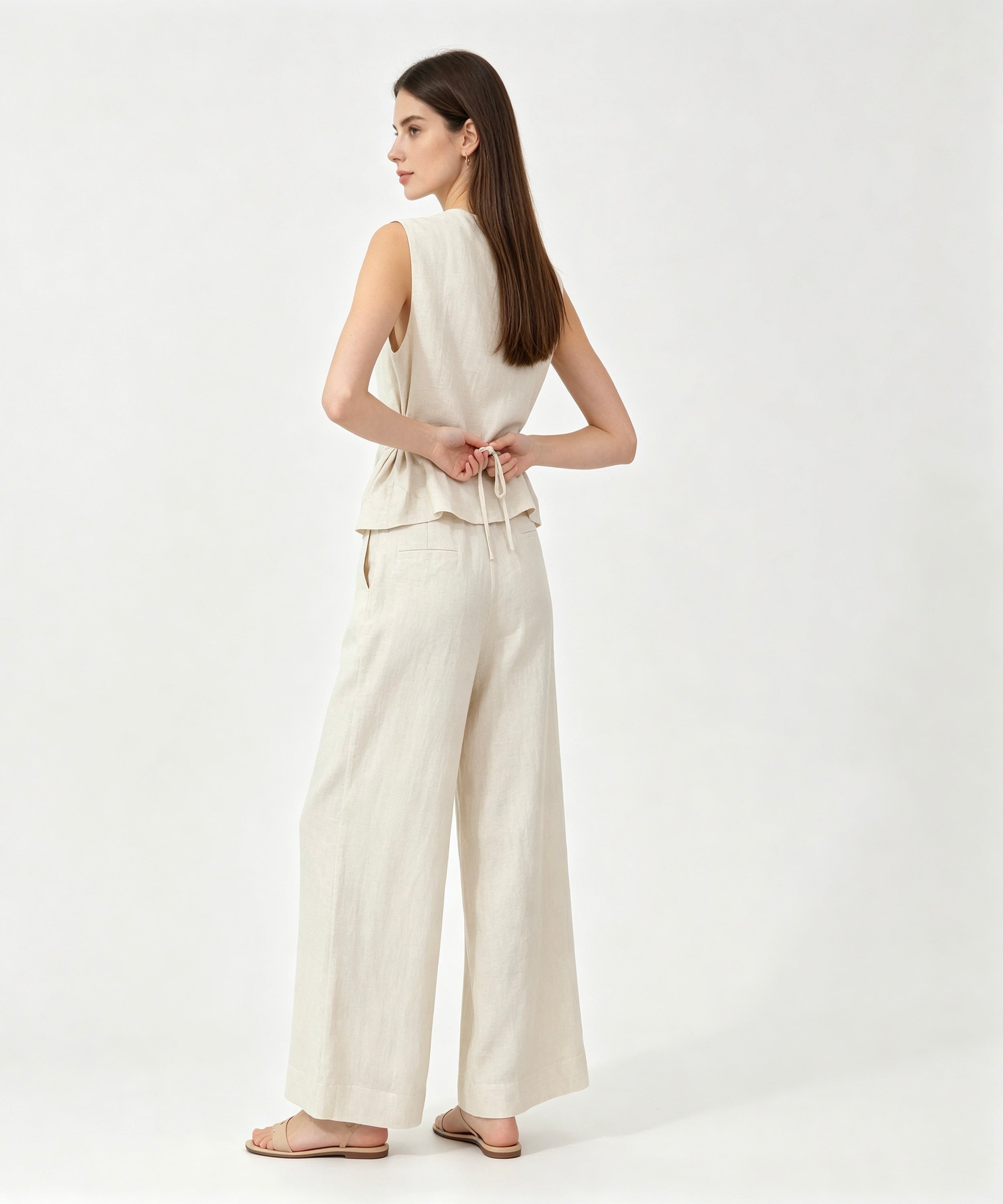 Woman wearing a white sleeveless top and wide-leg pants on a white background