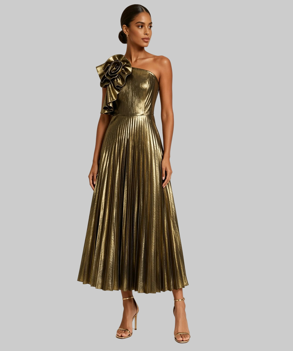 A model wearing a metallic gold one-shoulder midi dress with a large decorative ruffle on the shoulder and a pleated skirt, paired with nude high-heeled sandals against a plain white studio background.