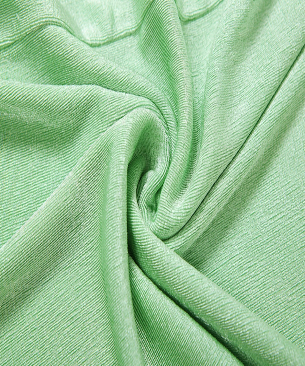 A close-up of light mint green ribbed fabric with soft folds and a twisted swirl pattern.