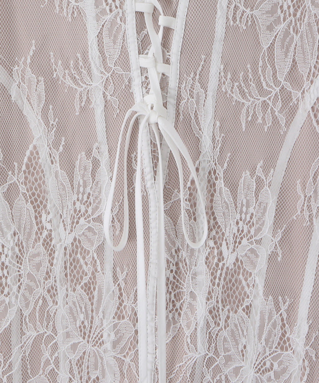 Close-up of a white floral lace garment with a lace-up front and sheer mesh overlay.