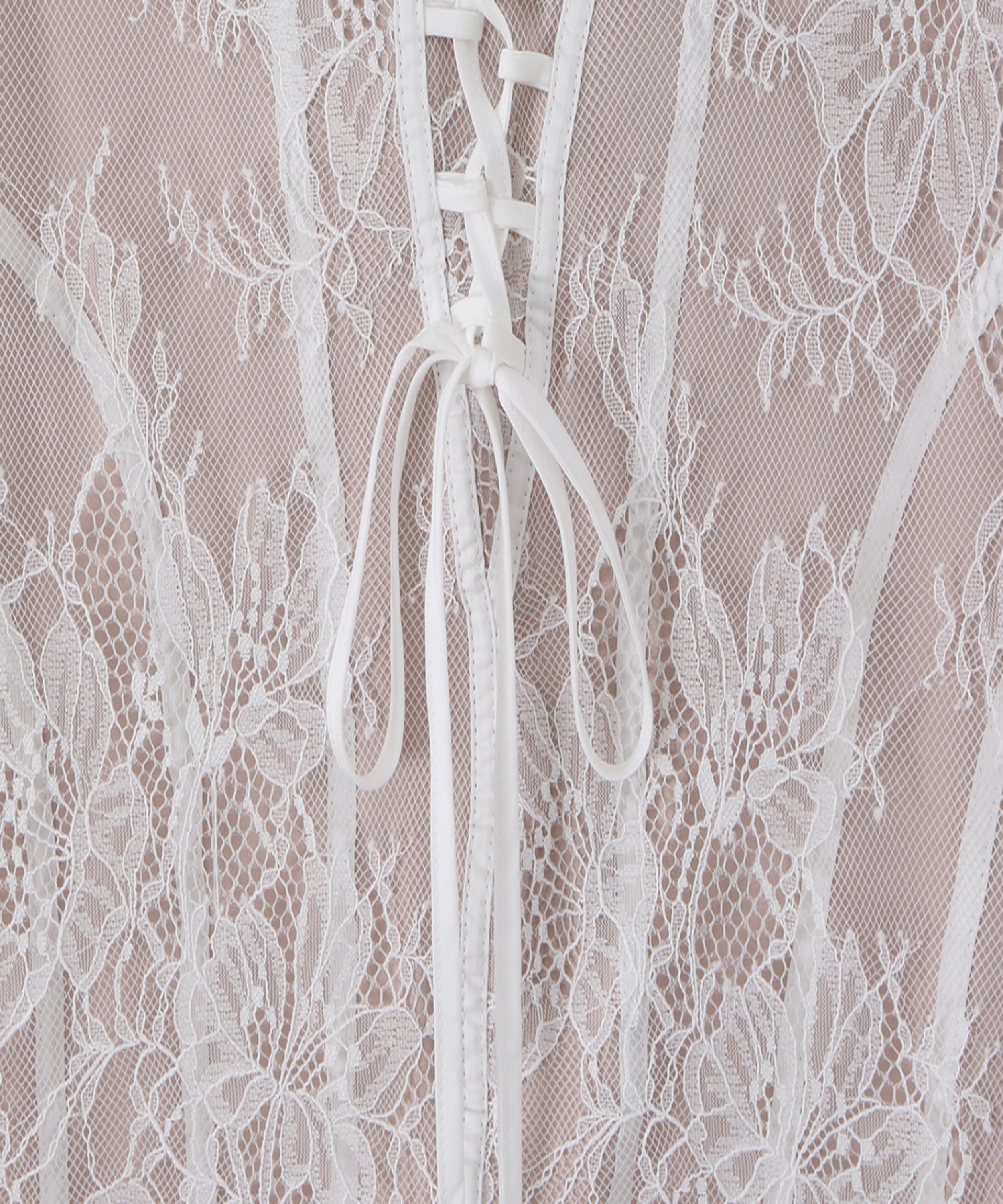 Close-up of a white floral lace garment with a lace-up front and sheer mesh overlay.