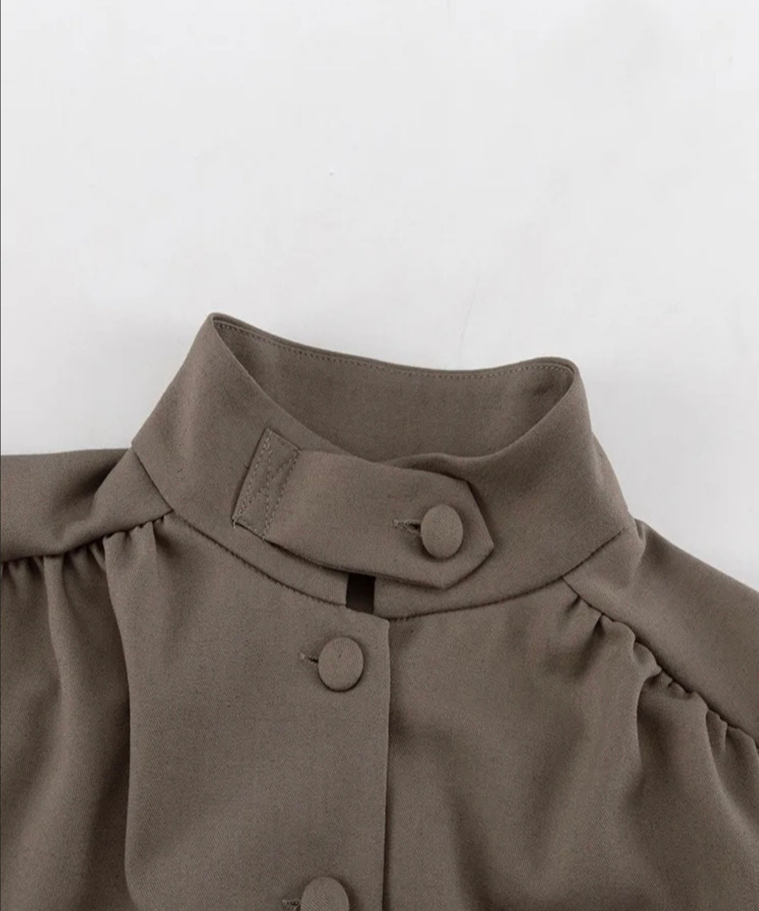 Close-up of a brown garment with buttons on a white background