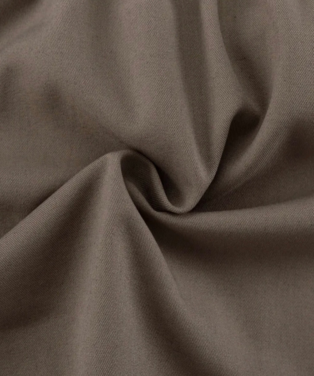 A close-up of draped fabric in a muted taupe-brown color, showing the material texture and soft folds.