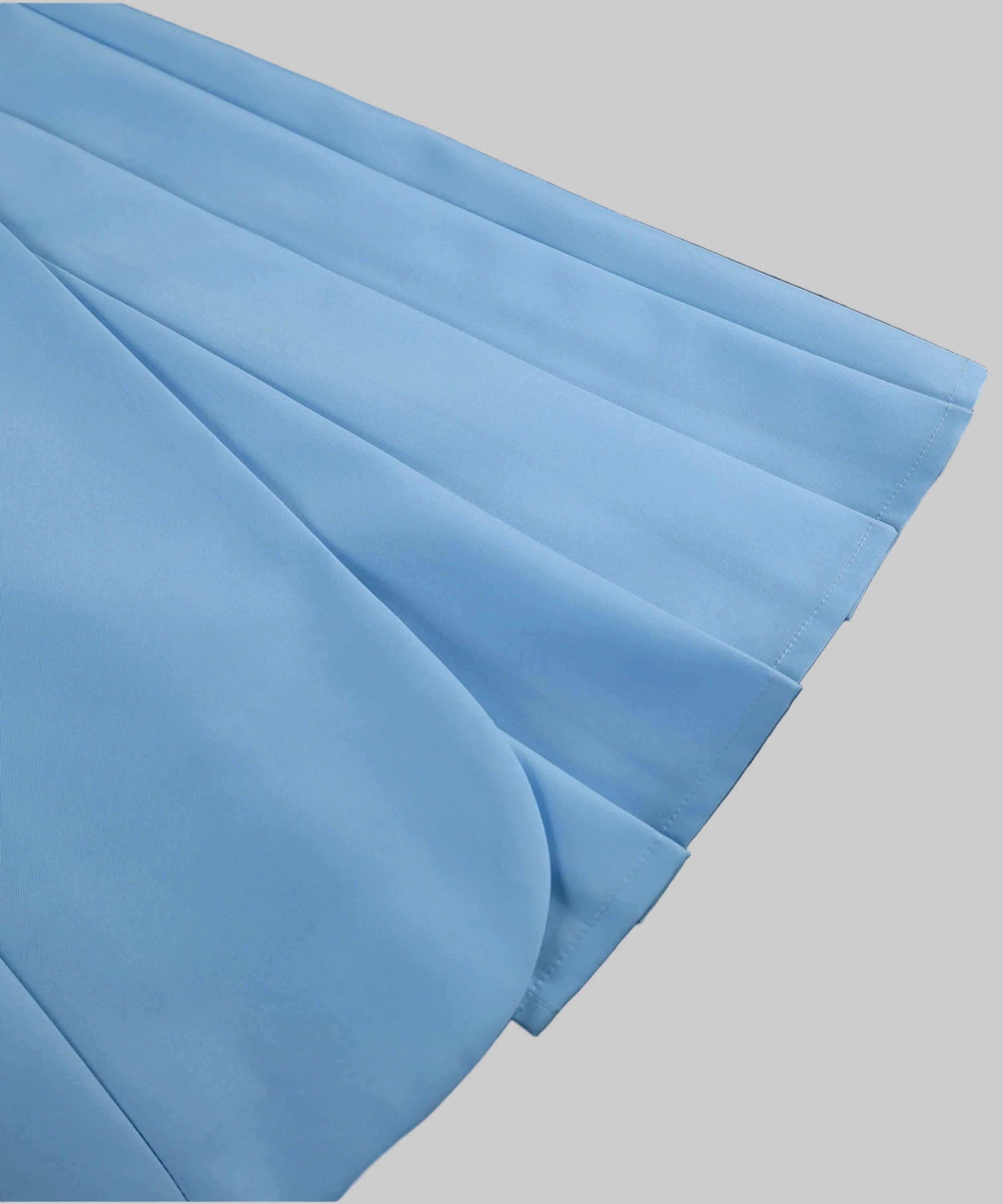 A close-up of light blue pleated fabric, showing the texture and folds against a white background.