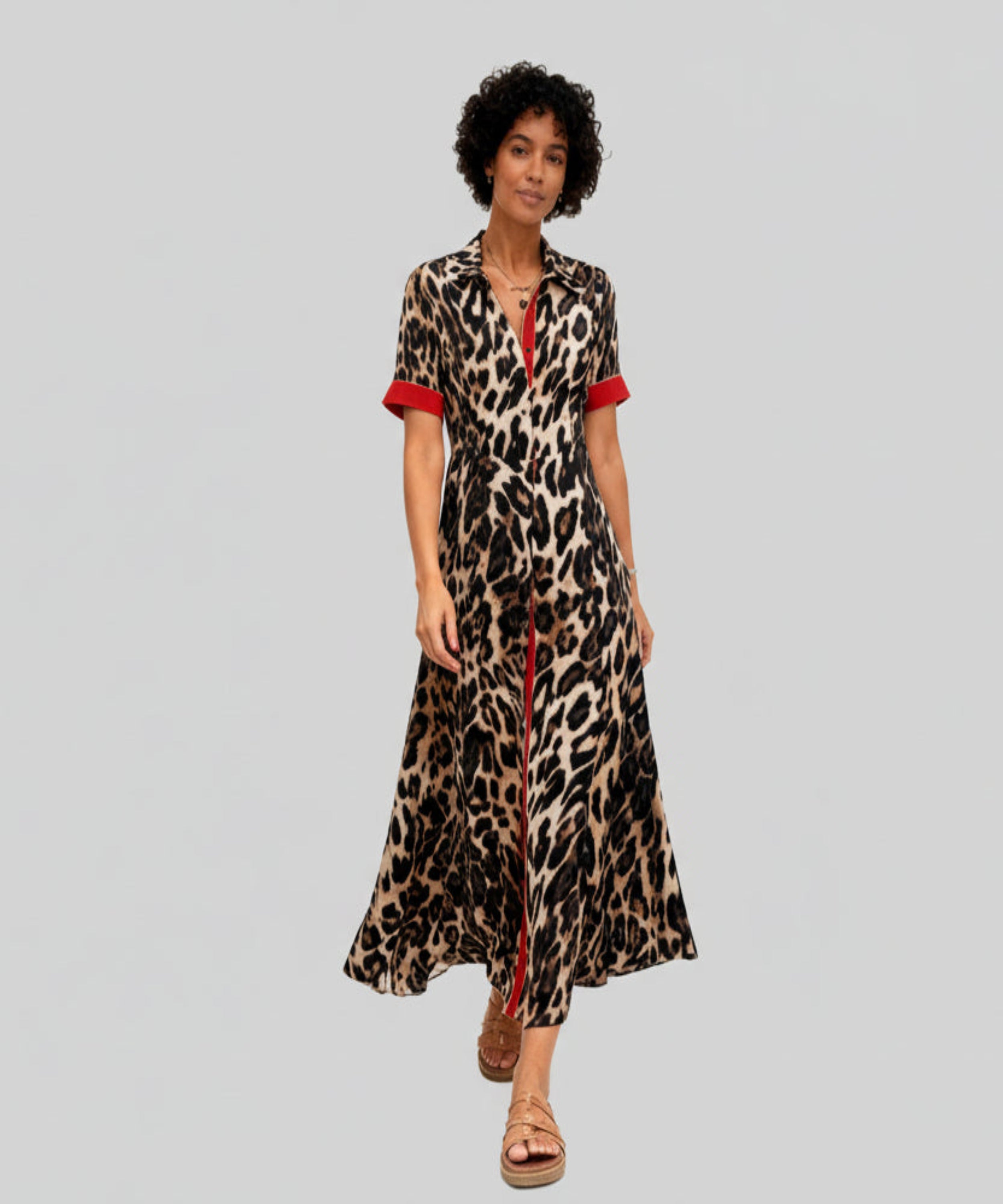 Woman wearing a leopard print dress with red accents on a white background