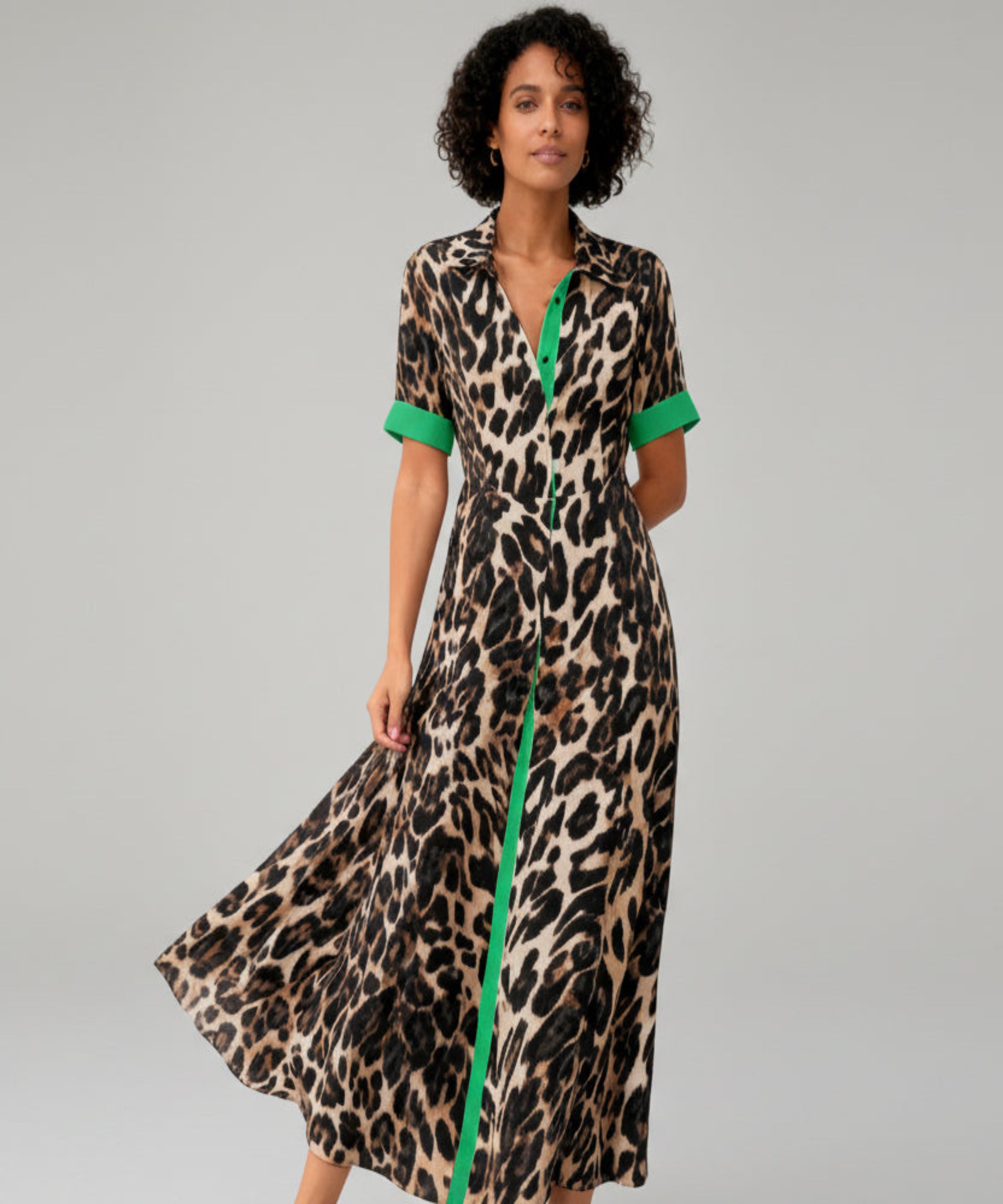 Woman wearing a leopard print dress with green accents on a white background