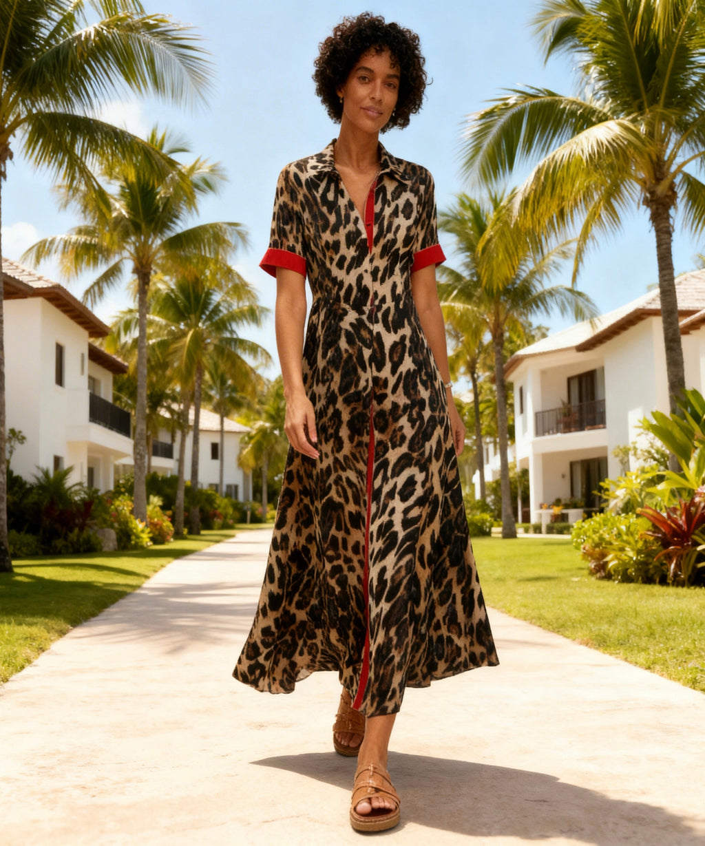 Woman in a leopard print dress walking on a path with palm trees and buildings in the background