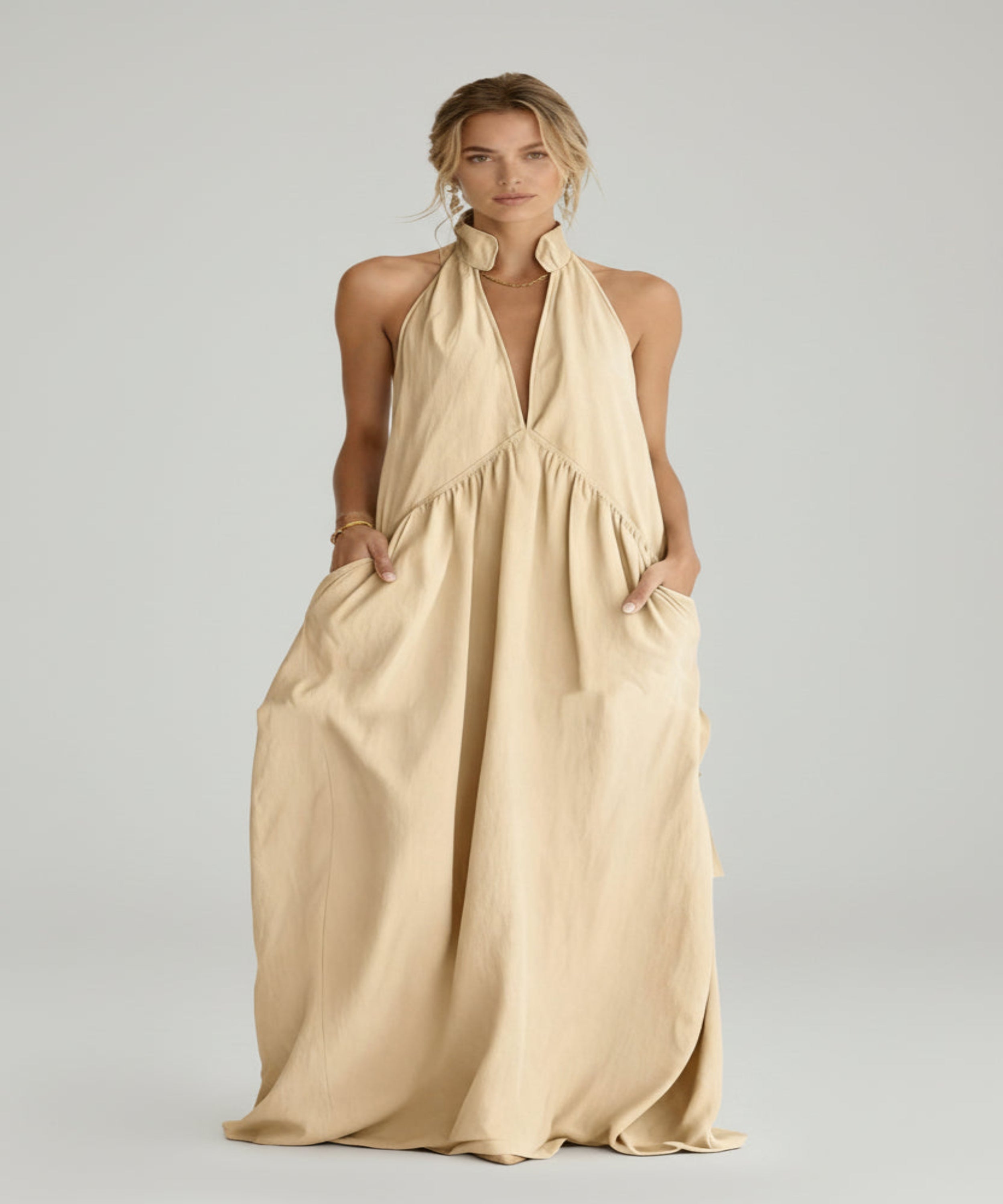 Woman wearing a beige halter neck dress on a white background