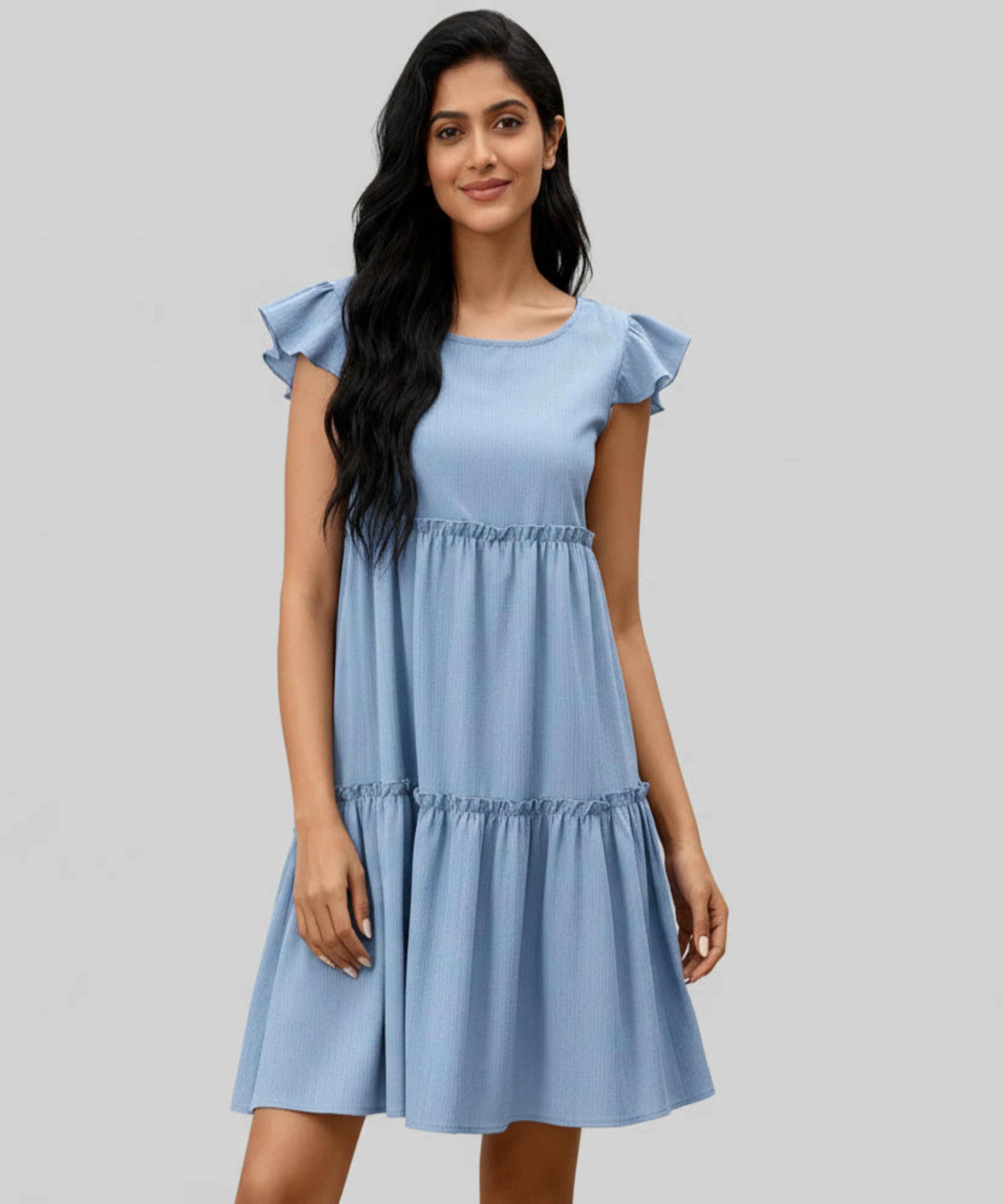 Woman wearing a blue dress with ruffled sleeves on a white background