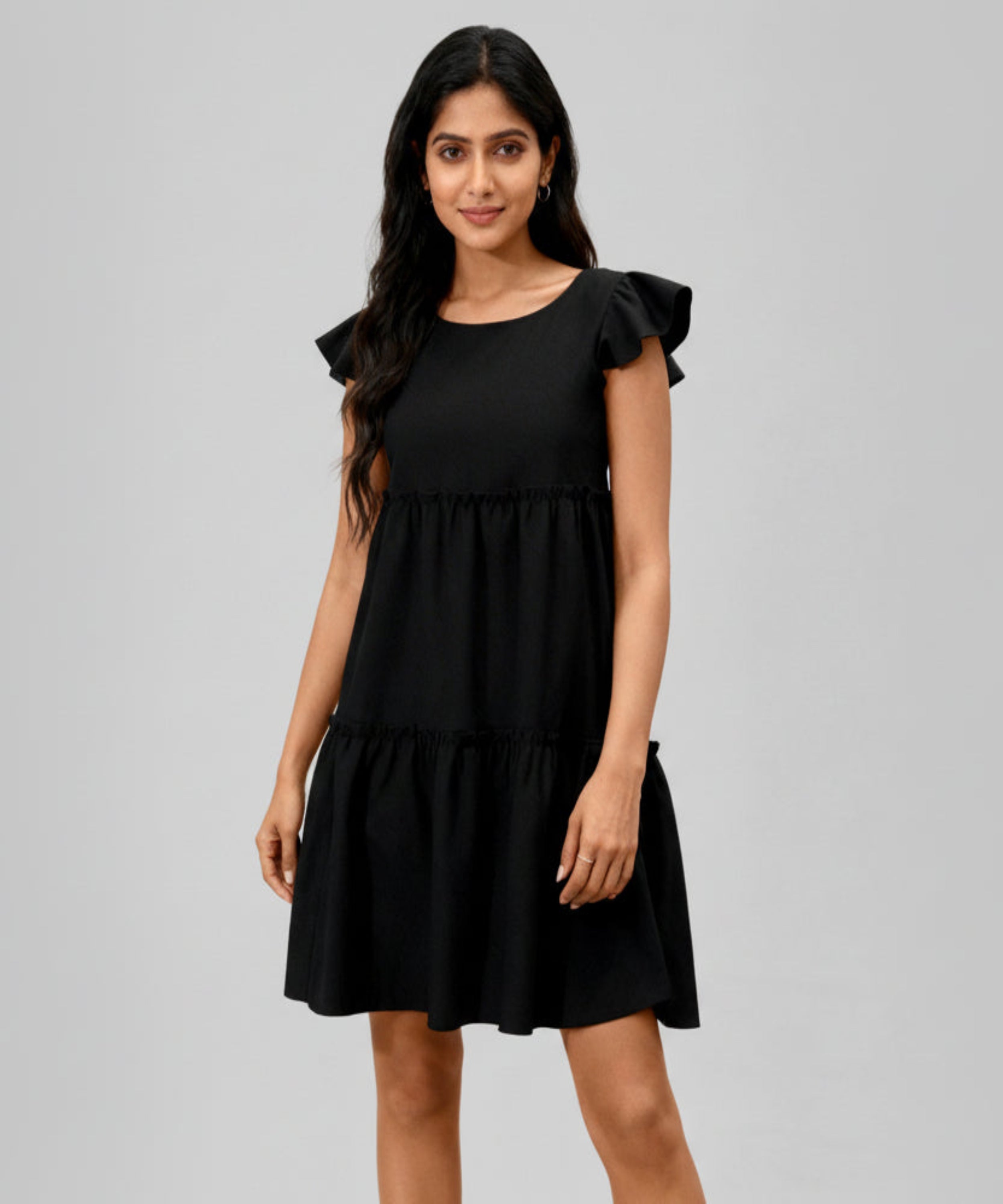 Woman wearing a black dress with ruffled sleeves on a white background