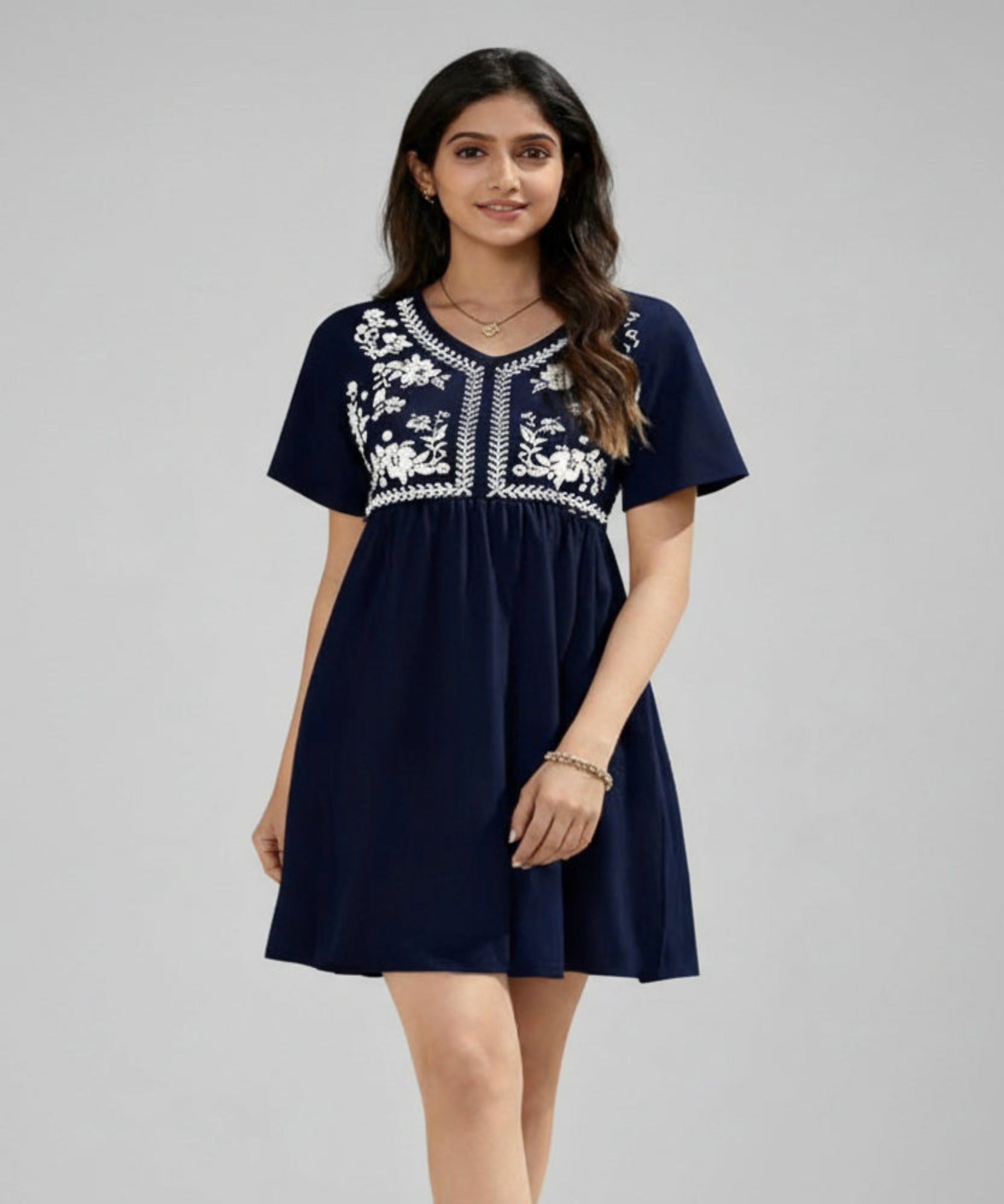 Woman wearing a navy blue dress with white embroidery on a white background