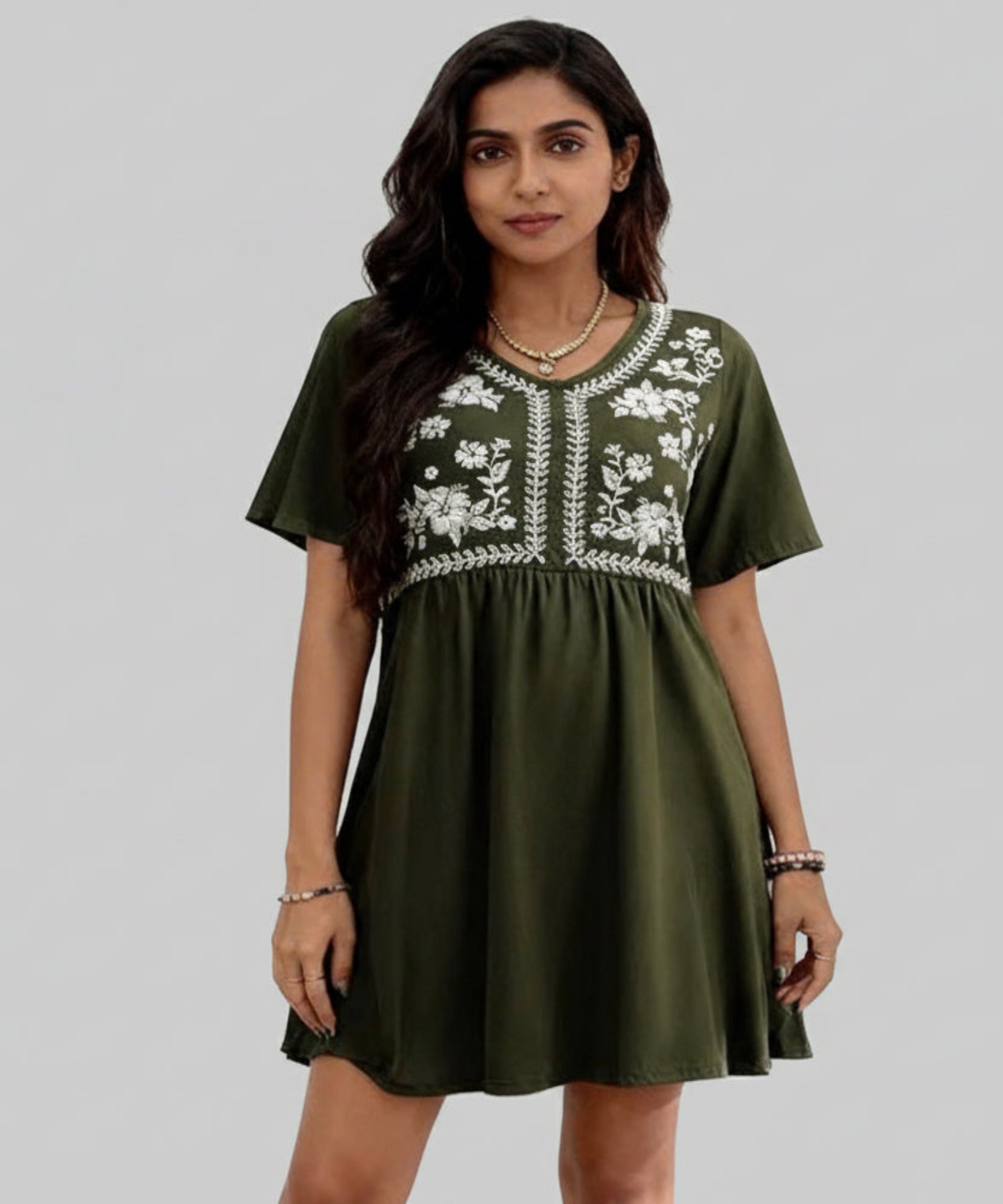 Woman wearing an olive green dress with white floral embroidery on a white background